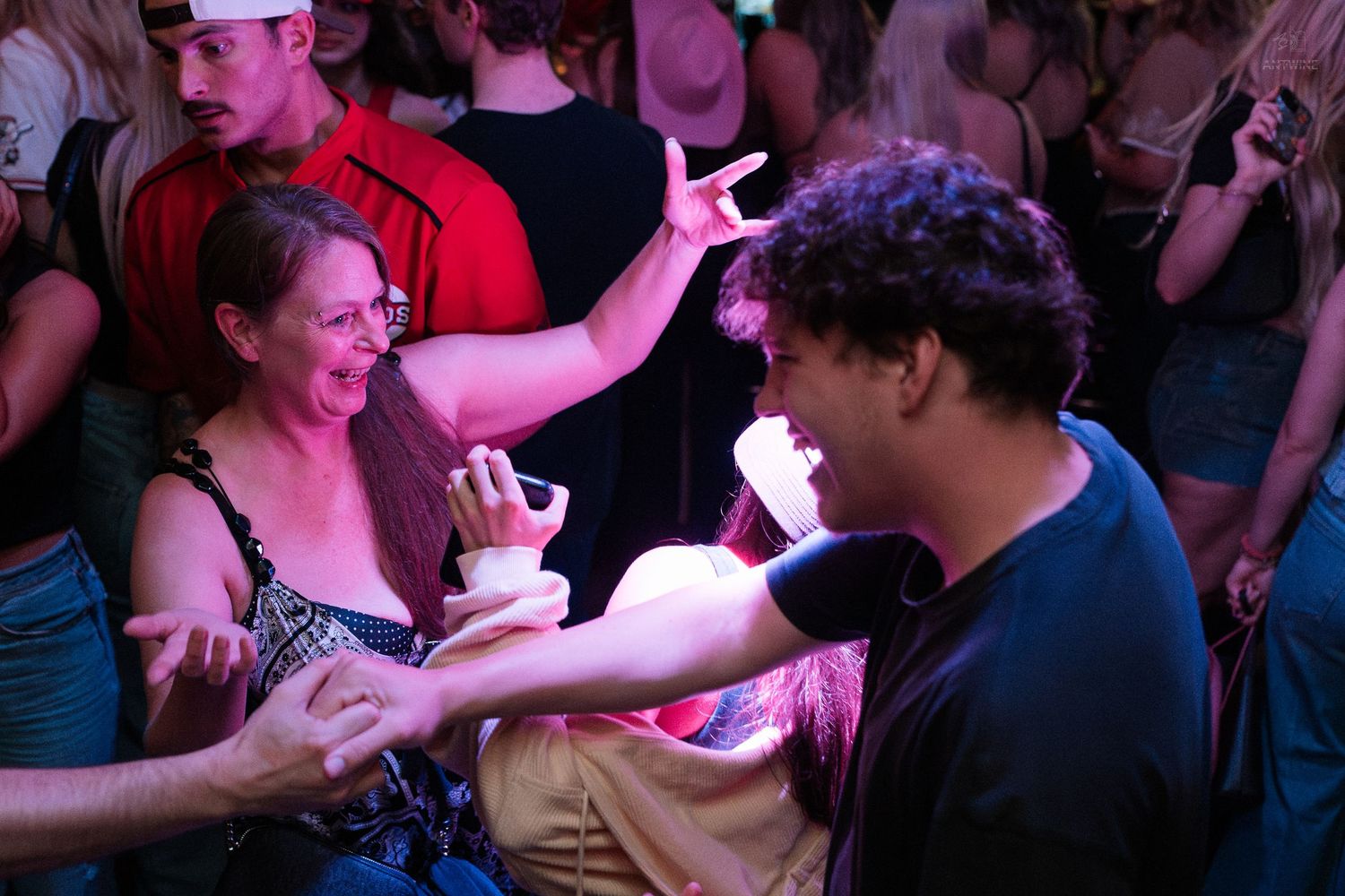 Two people sharing drinks and dancing at a lively nightclub event.