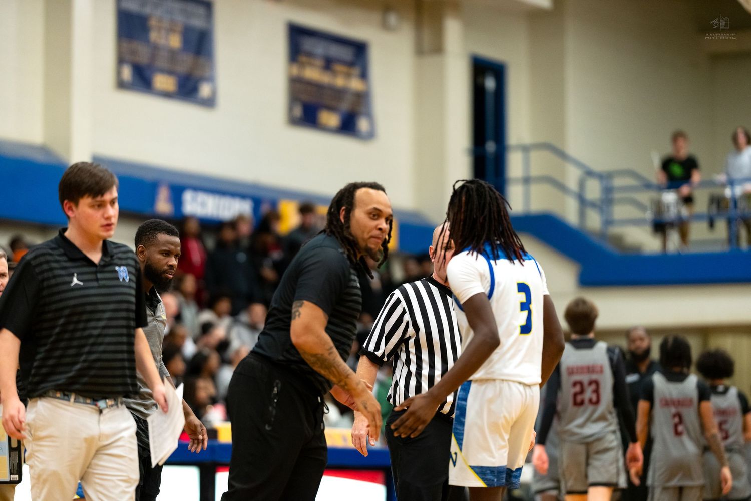 A coach and referee interact with player number 3 during a high school basketball game.