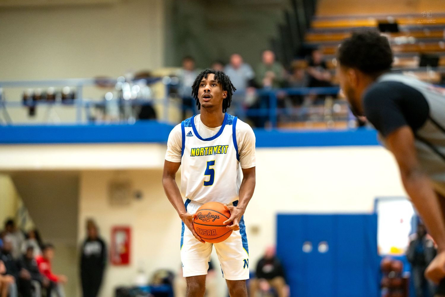 High school basketball player #5 in white uniform prepares for free throw in blue and white gymnasium.