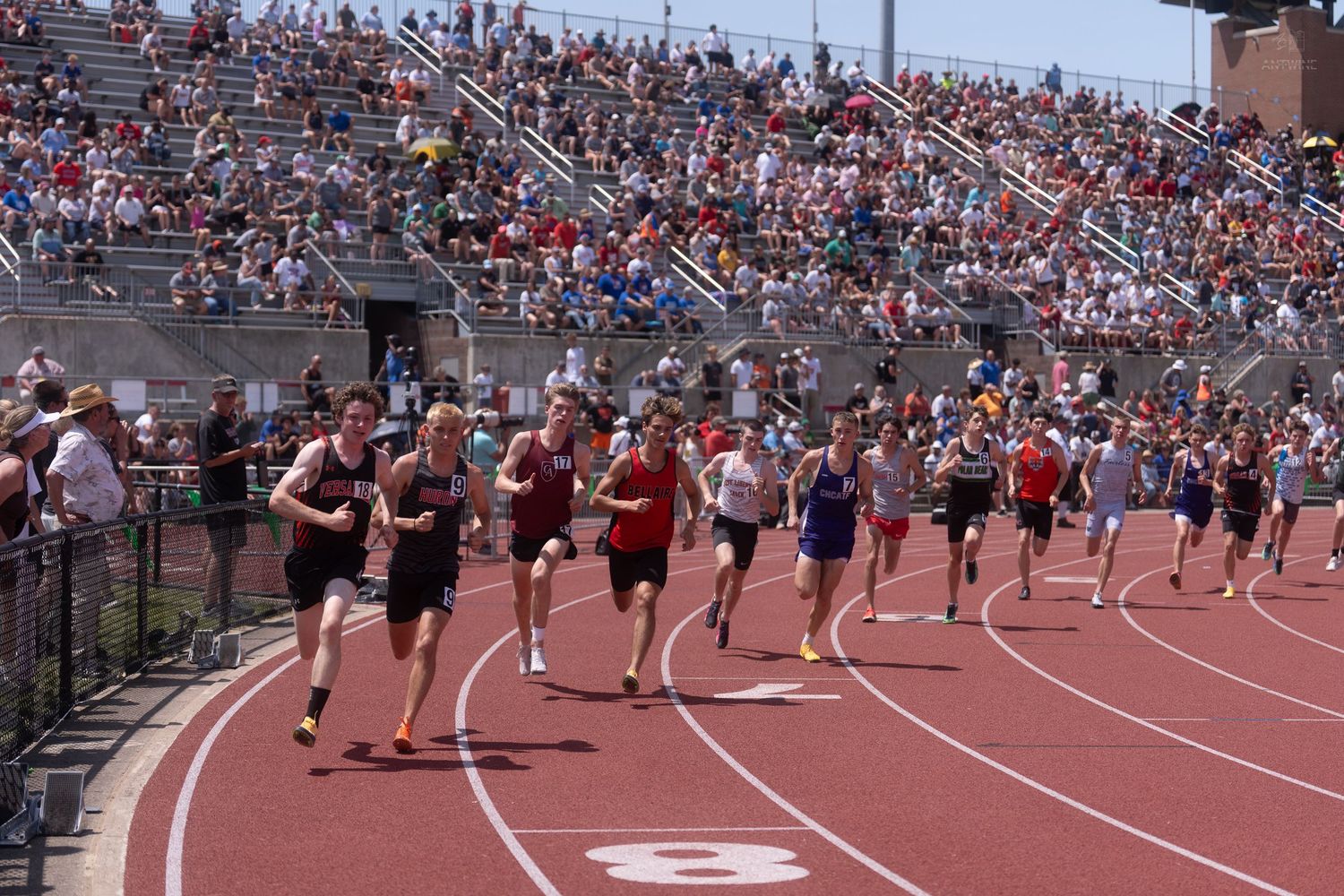 Runners sprint from the starting line in a middle distance race at a packed Ohio State University track meet.
