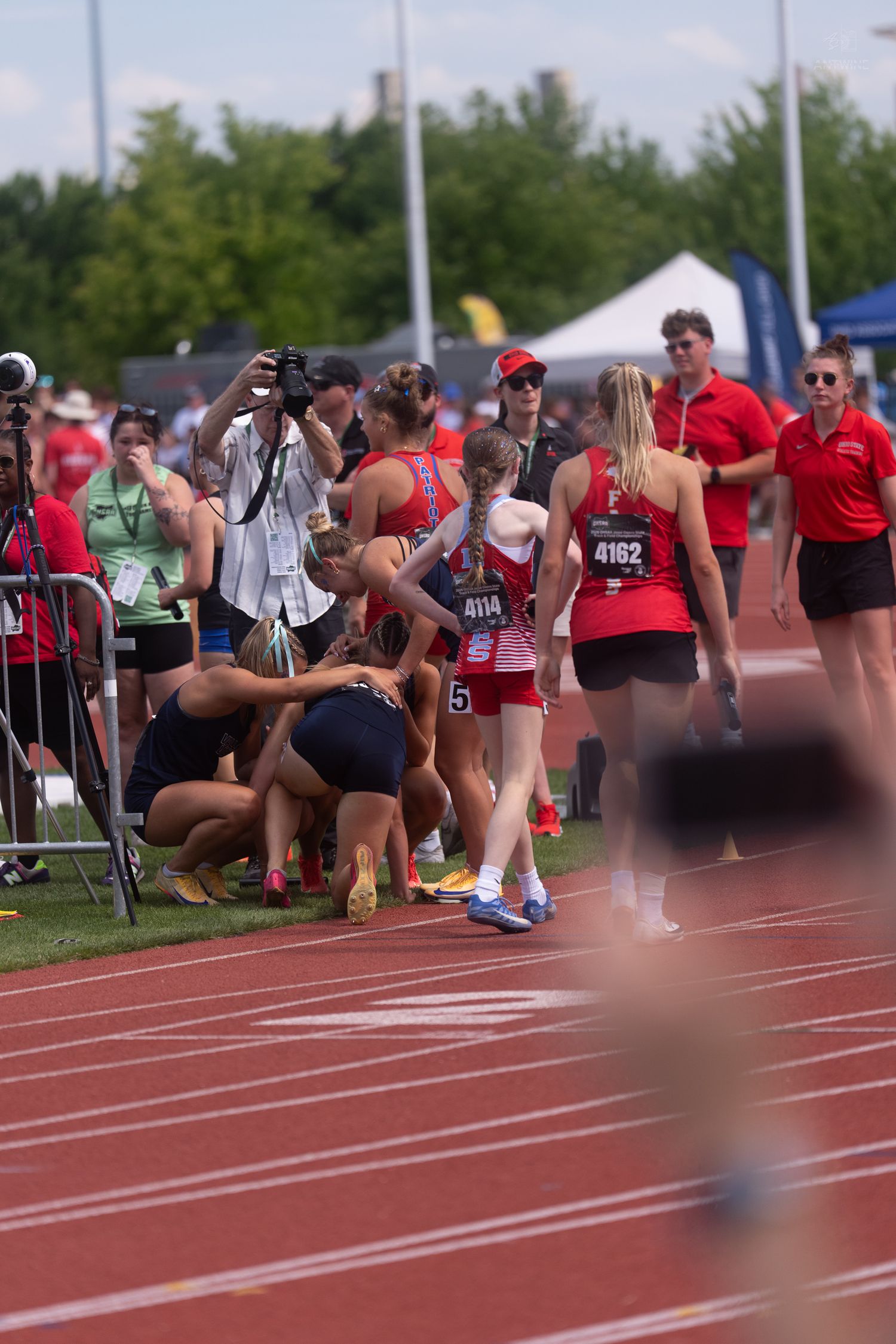 Female runners wearing red uniforms with bib numbers 4162 and 4114 walk after finishing a relay race event.