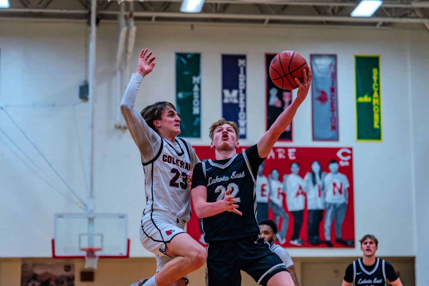 High school basketball player number 22 drives to the basket past a defender during a game.