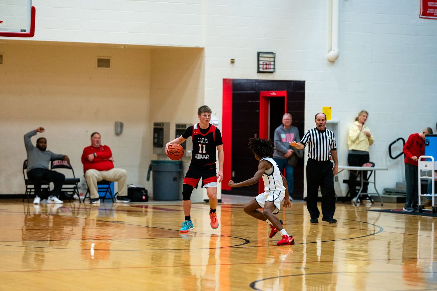 Player number 11 dribbles the ball down the court during a high school basketball game.