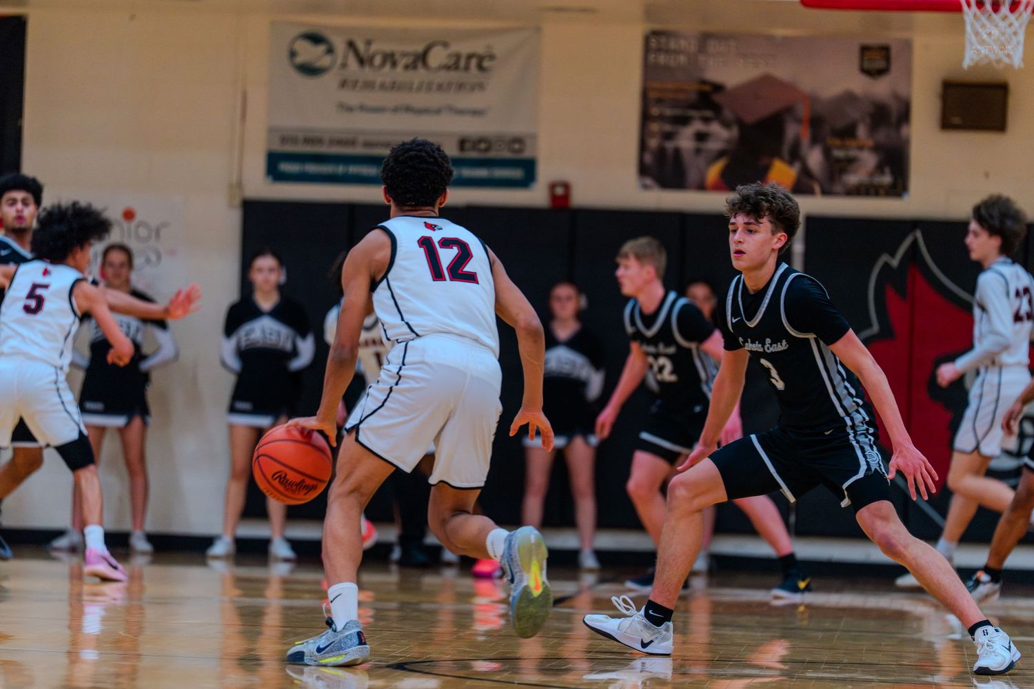 Lakota East player number 12 dribbles past defender during a high school basketball game.