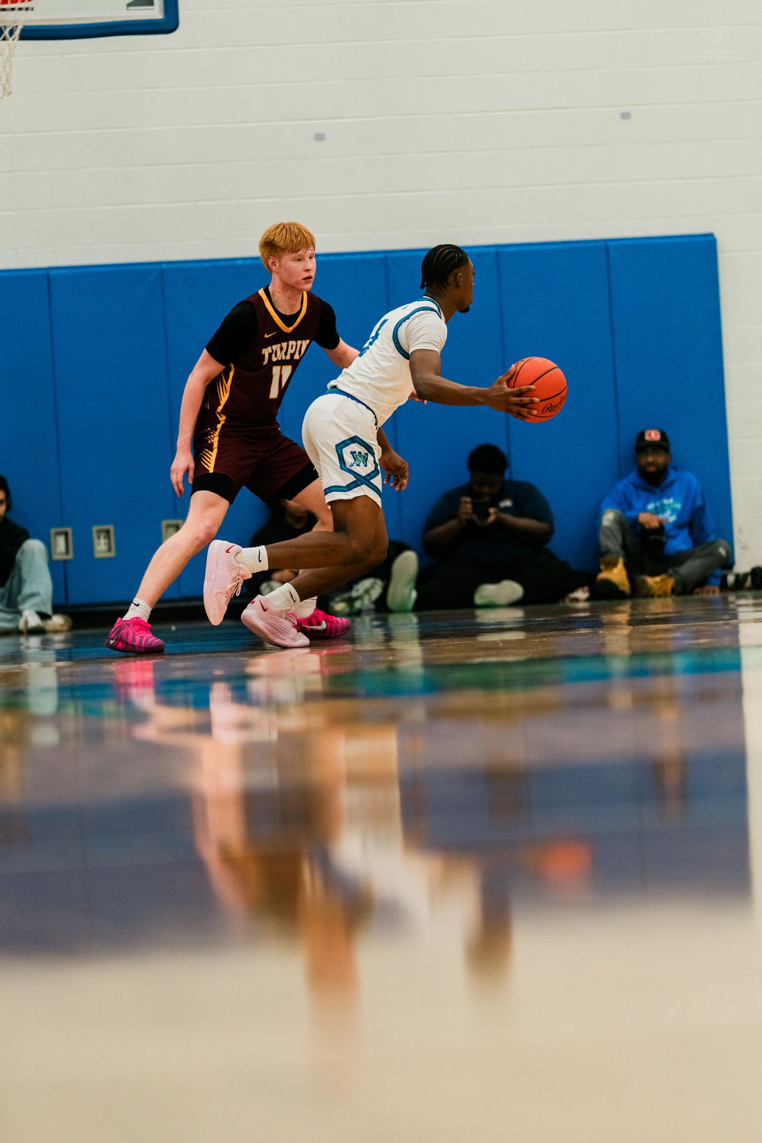 A Xavier Warriors player dribbles past a Turpin defender during a high school basketball game.