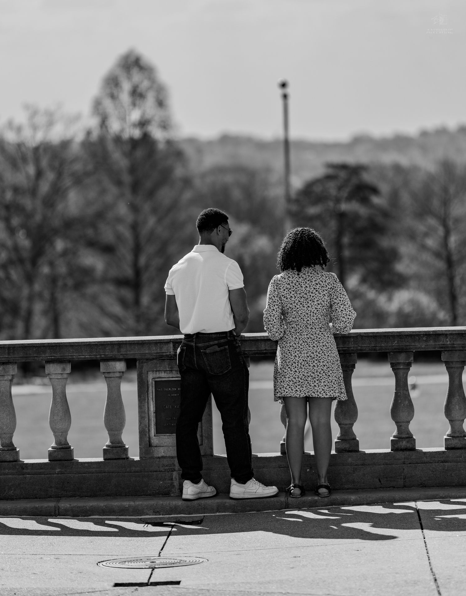 Monochrome photo of man and woman standing side by side at ornate stone railing.