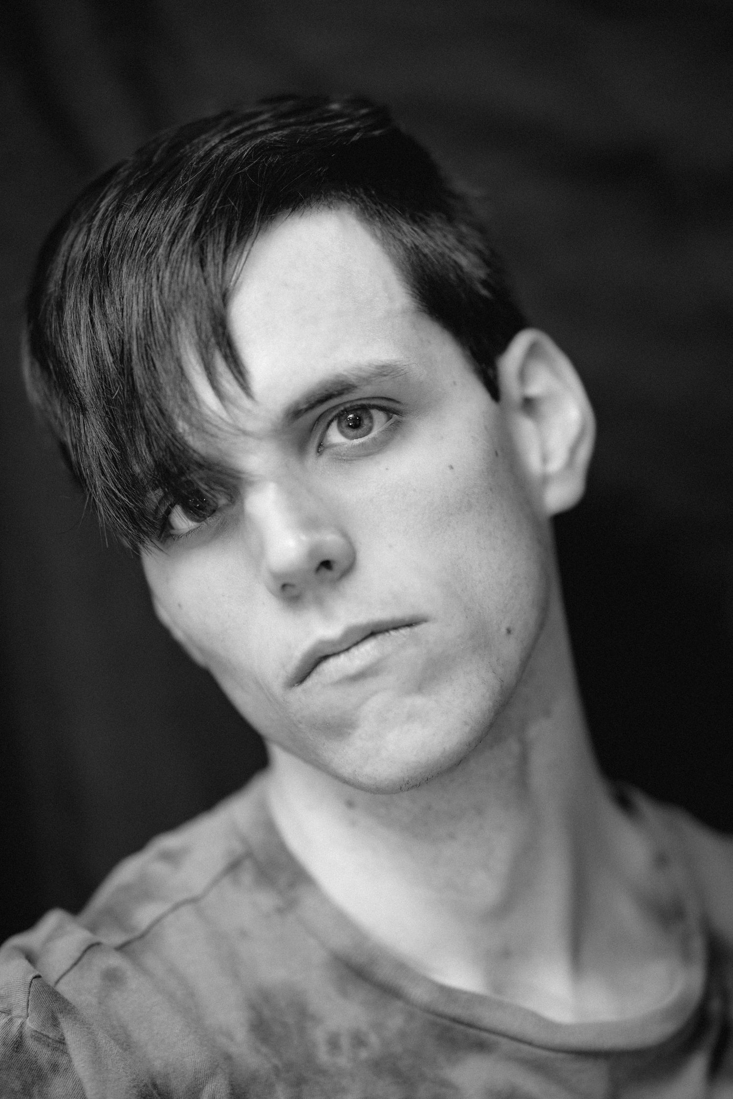 Black and white portrait of young man with dark swept hair in casual t-shirt.