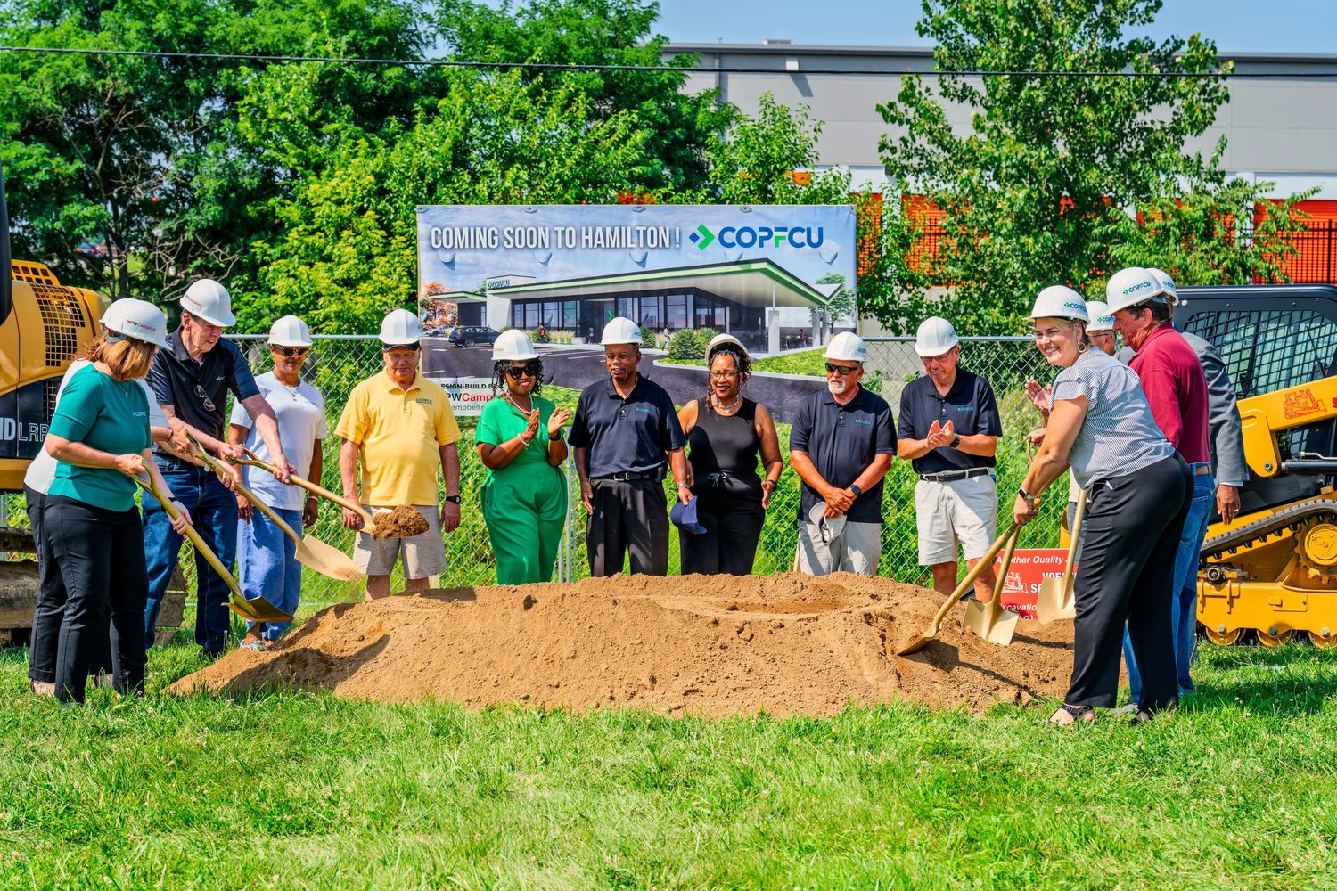 Team of people in hard hats shoveling dirt at COPFCU new branch groundbreaking event.