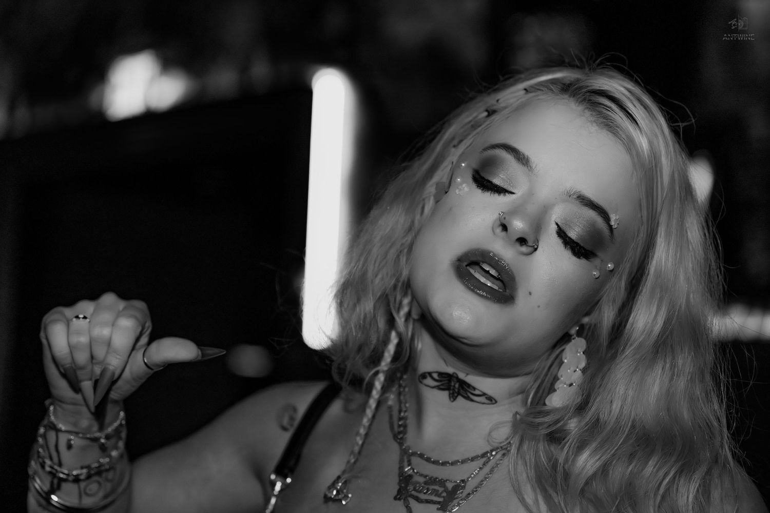 Black and white close-up portrait of blonde woman with jewelry and bold makeup.