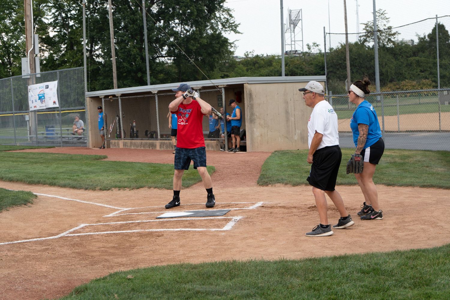 Adults playing softball on a dirt diamond field during an outdoor recreational game on a sunny day.