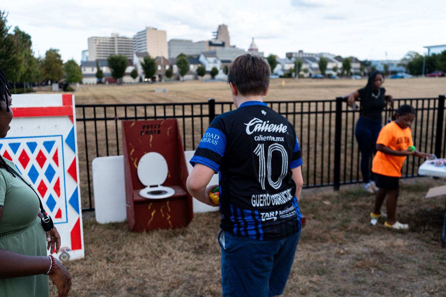 Person holds a toilet seat ring game prop at an outdoor charity carnival fundraiser event.