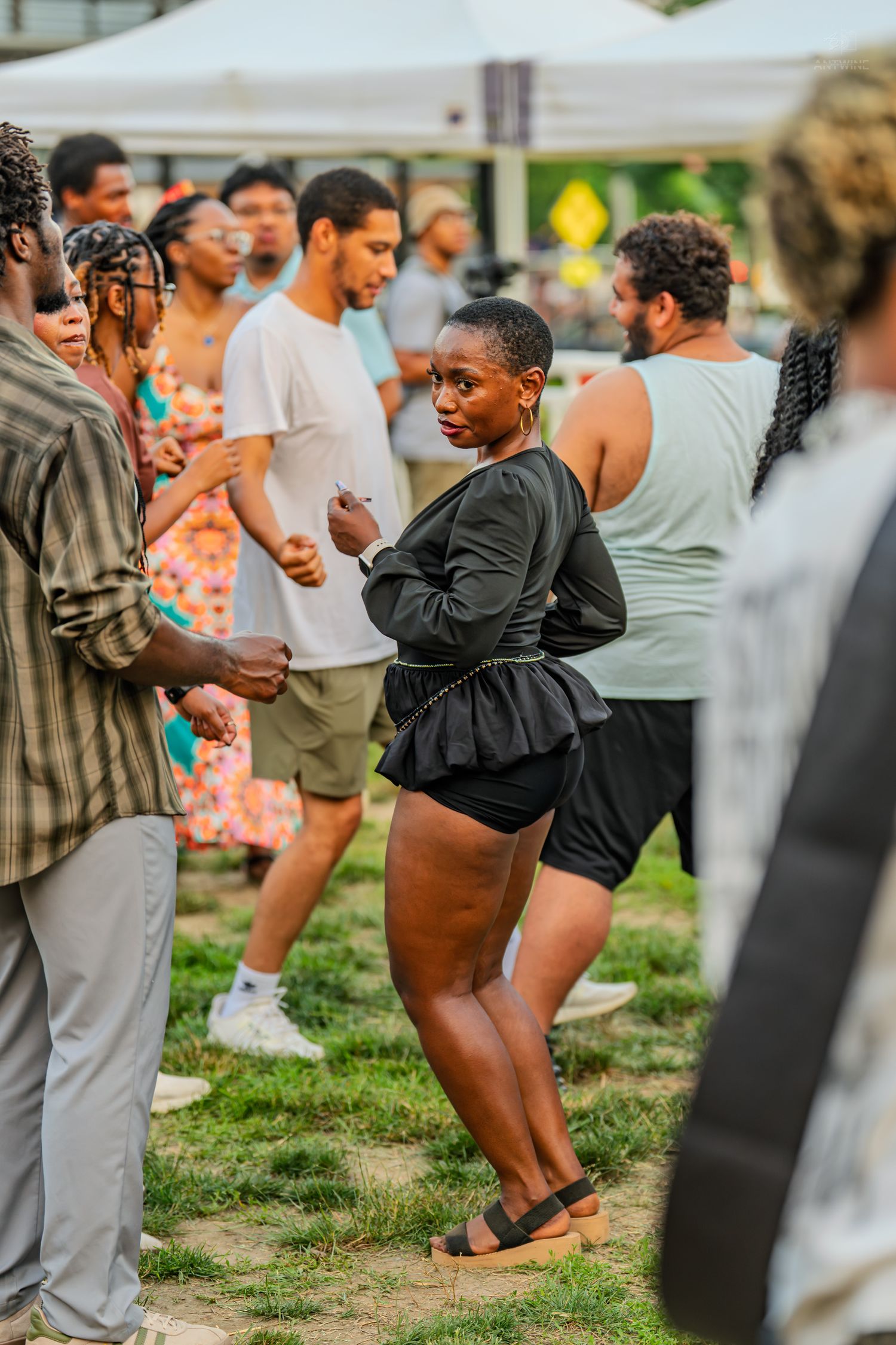 Black woman in black outfit dancing at an outdoor Juneteenth block party celebration.
