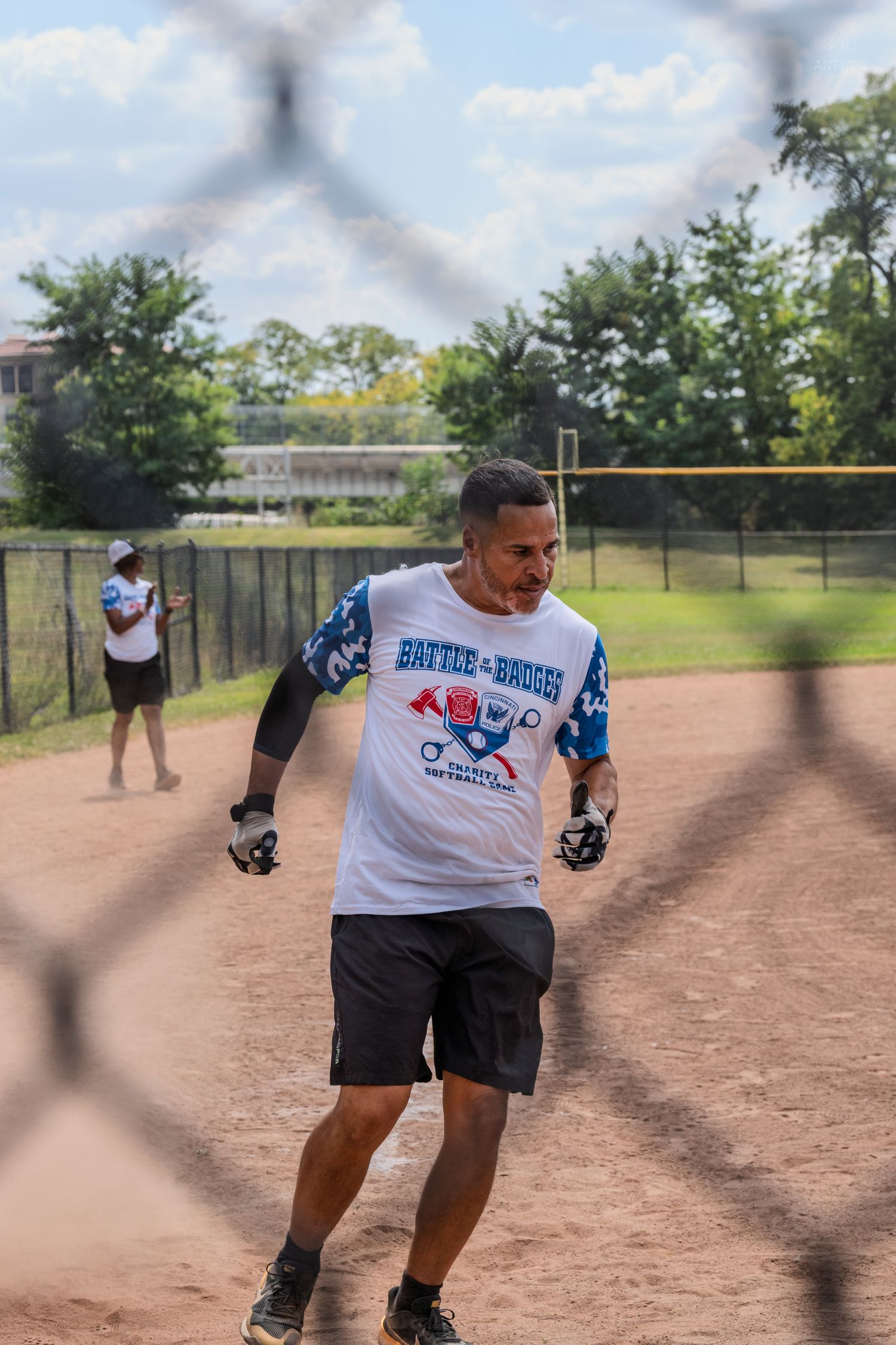 A player in a Battle of the Badges jersey runs the bases during a softball game.