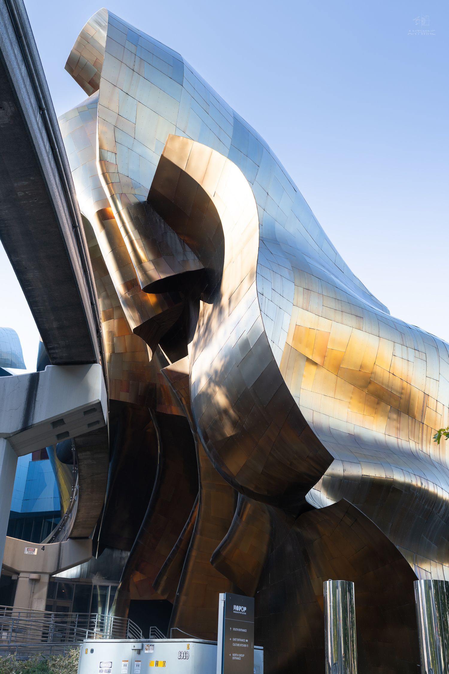 The striking curved metallic exterior of the MoPOP Museum of Pop Culture in Seattle gleams in sunlight.