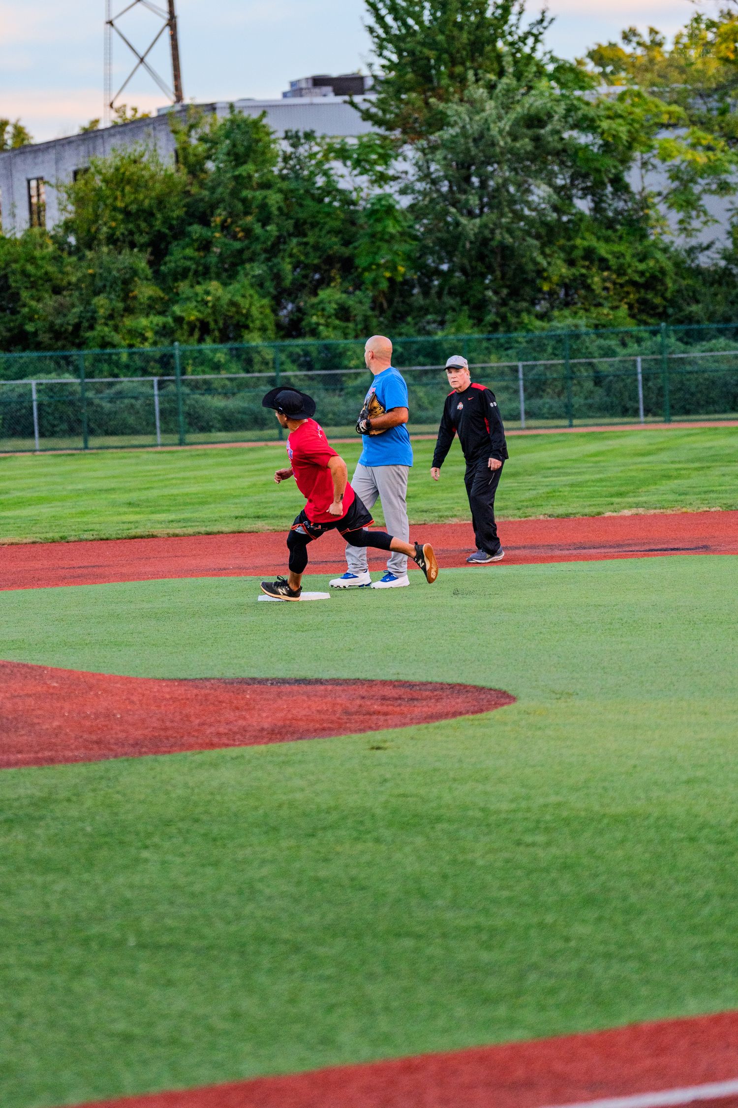 Baseball players near second base during recreational softball game on green field.