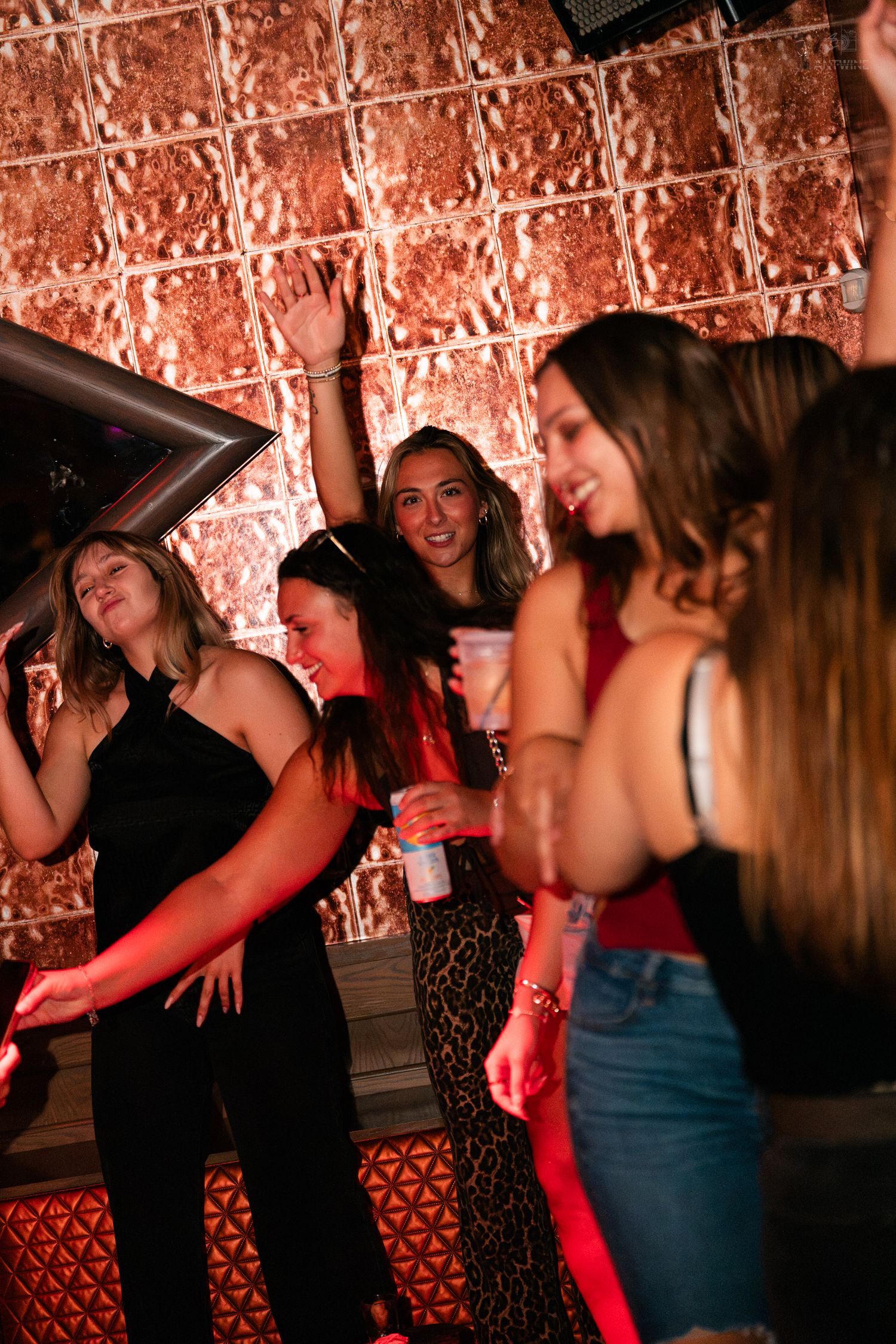 Women dancing and having fun under red lights at a nightclub party.