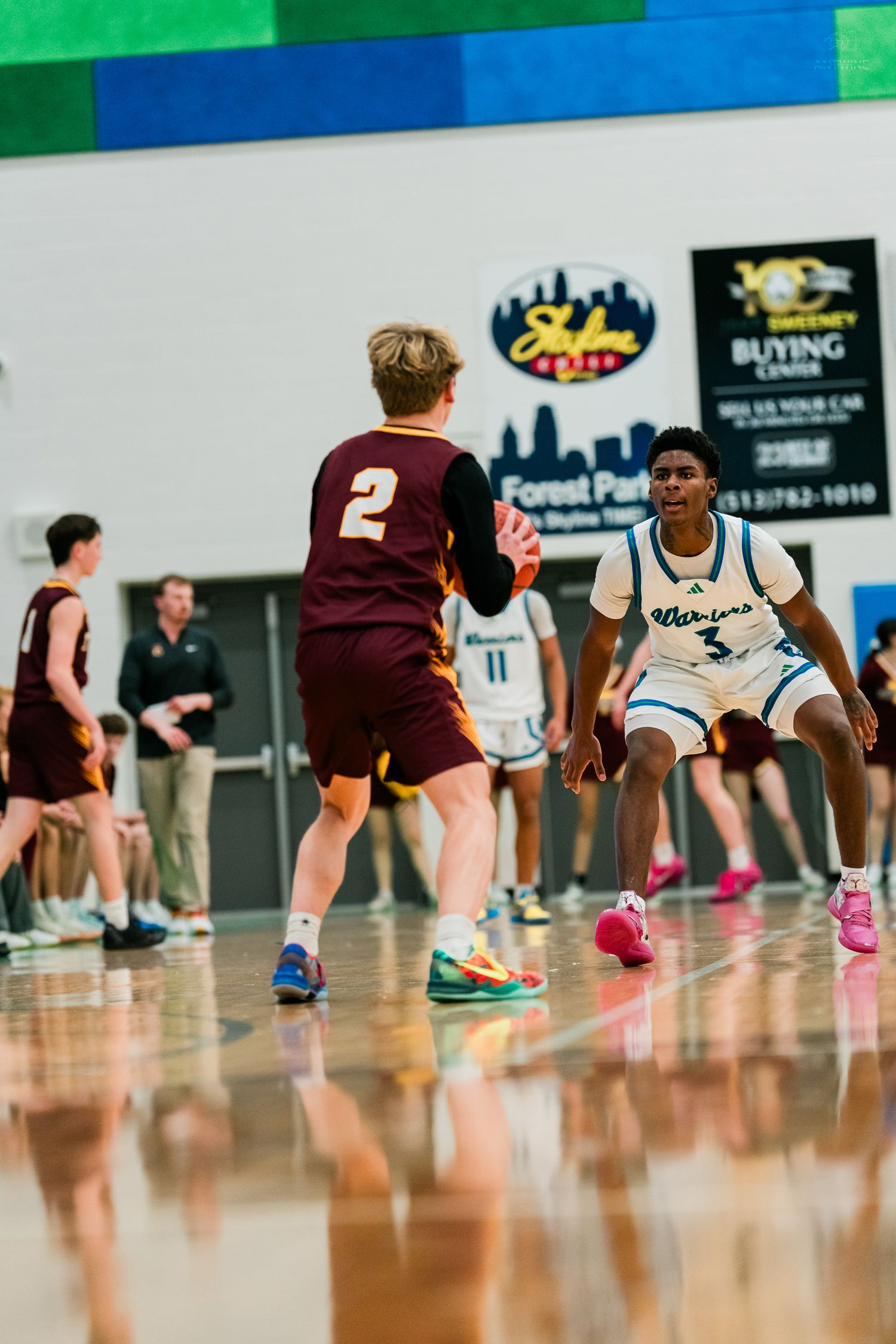 Warriors #3 in white uniform guards Turpin #2 during a high school basketball game on a reflective court.