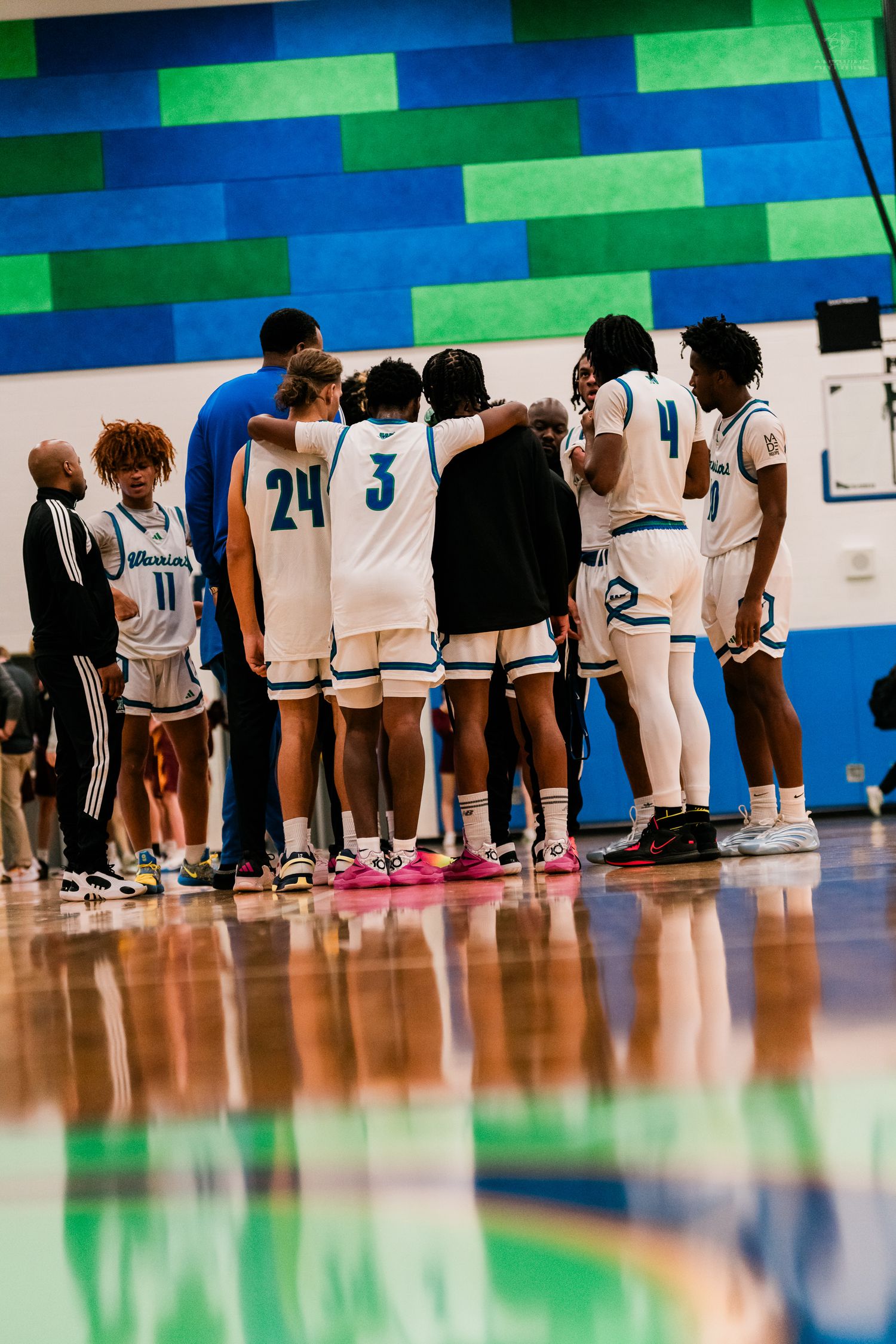 Winton Woods Warriors basketball team huddles on the sideline during a timeout in a home game.