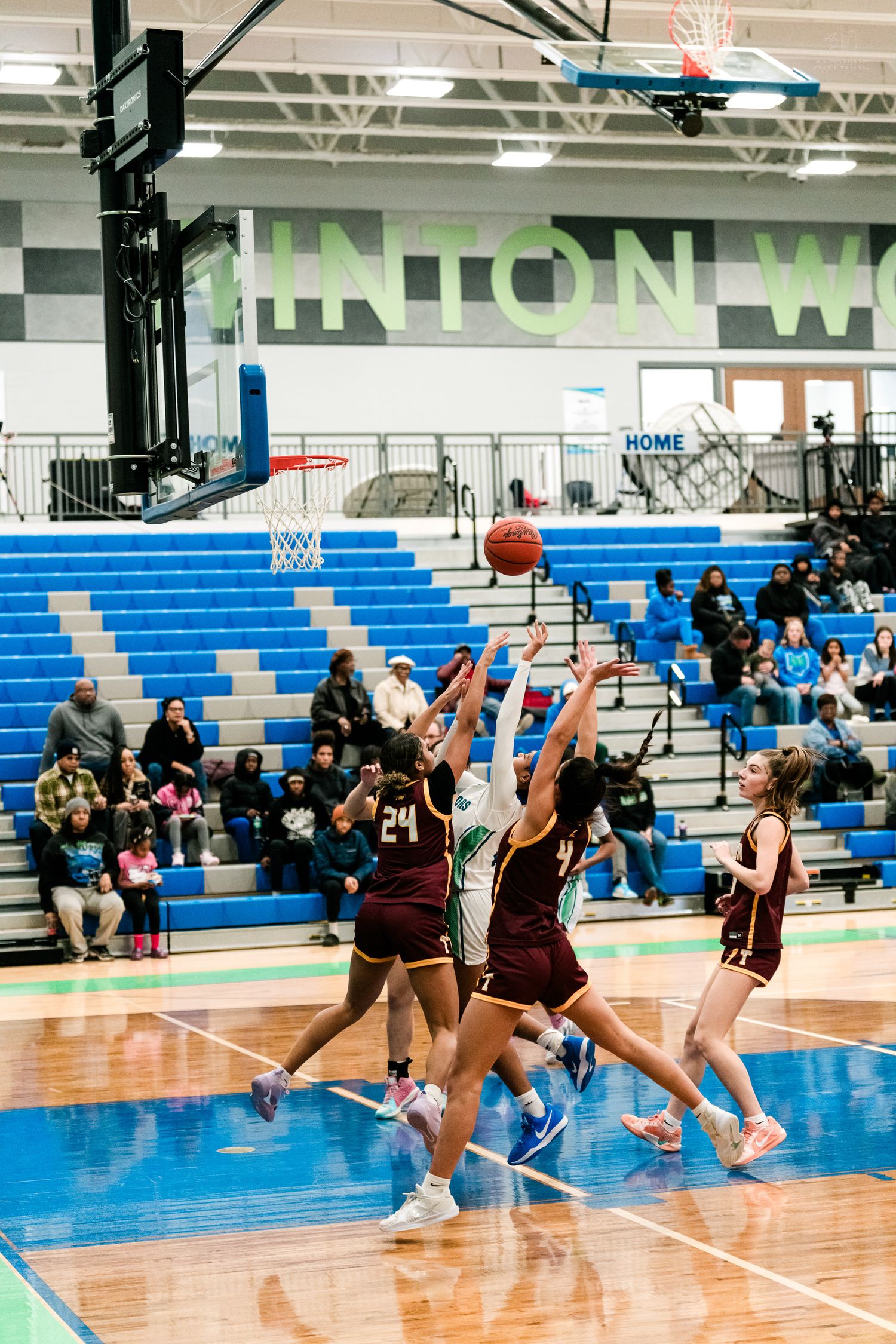Girls basketball players jump for the ball near the hoop during a game at Hinton Warriors home court.