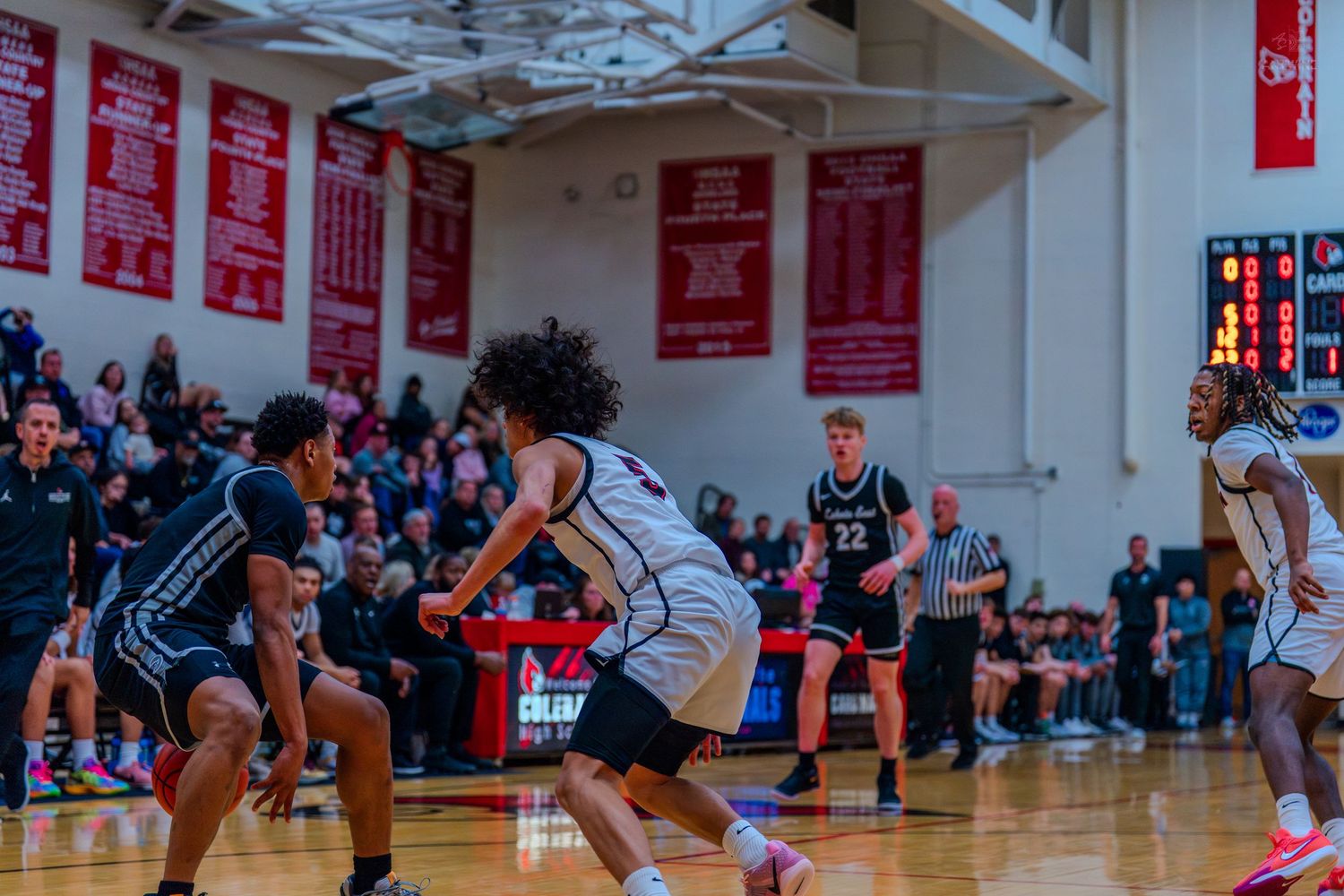 Lakota East basketball players defend against opponent during high school game in packed gymnasium.