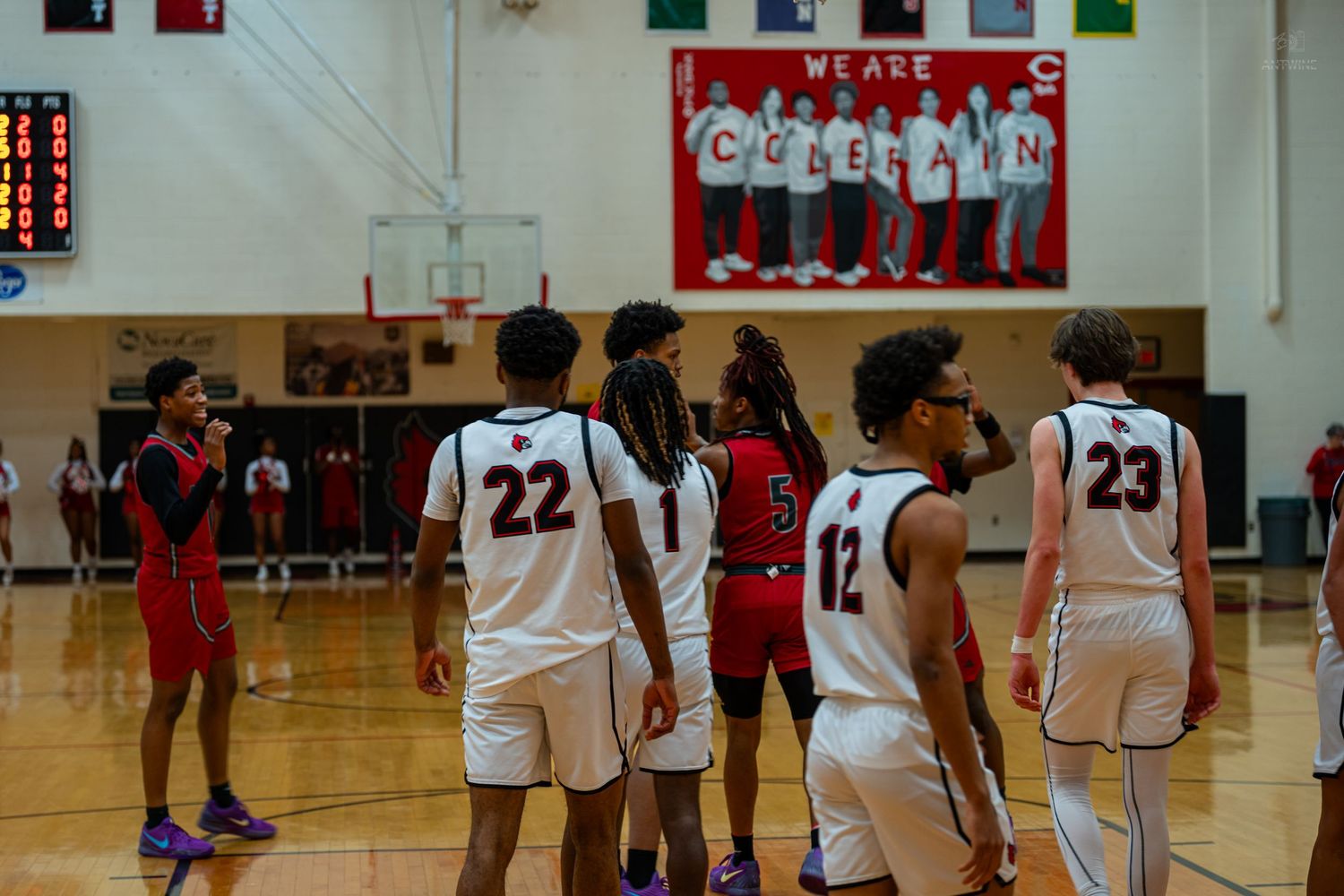 High school basketball players gather on the court during a game in a Coleman school gymnasium.