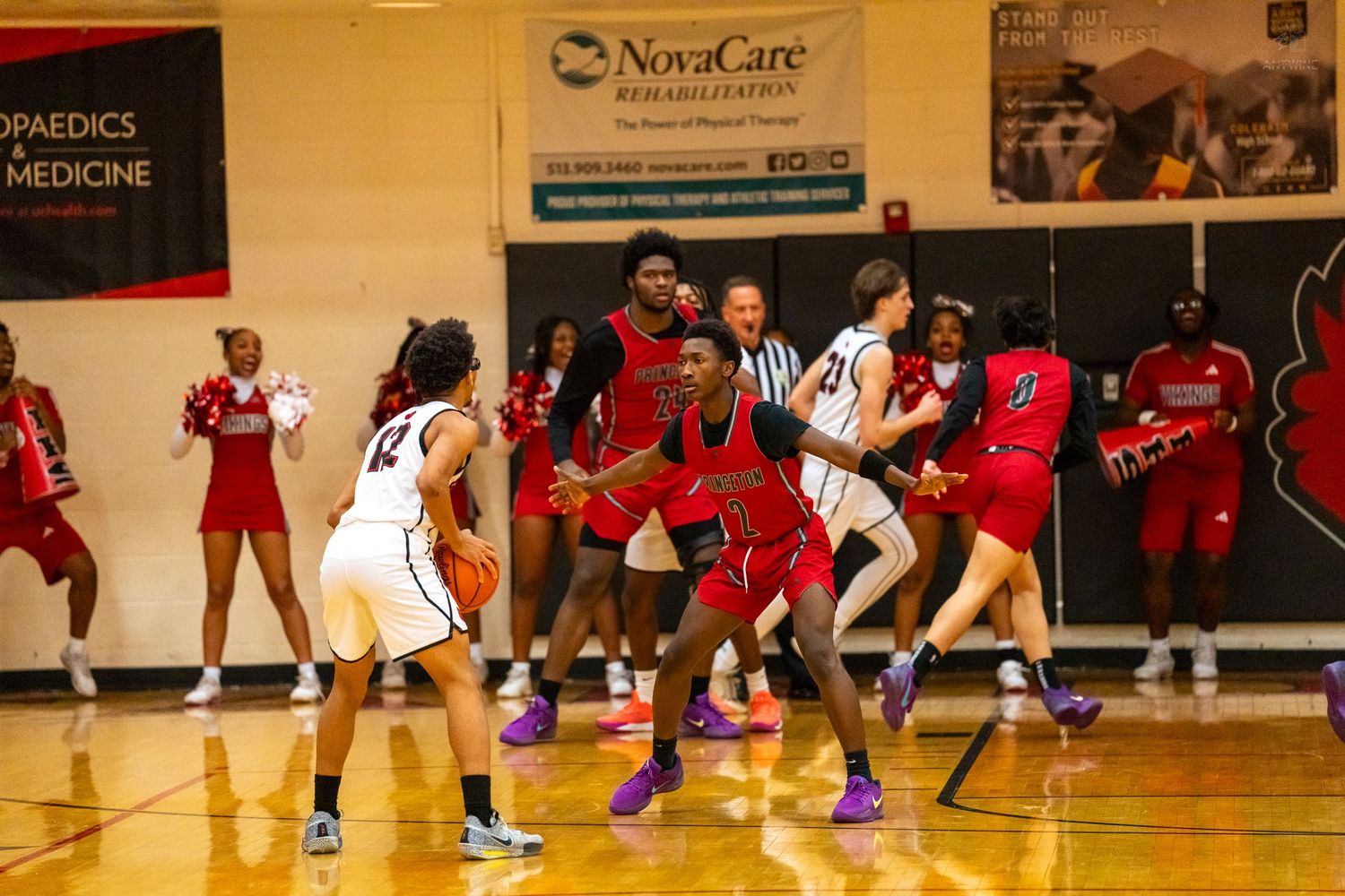 Red and white team players battle for position during indoor basketball game.