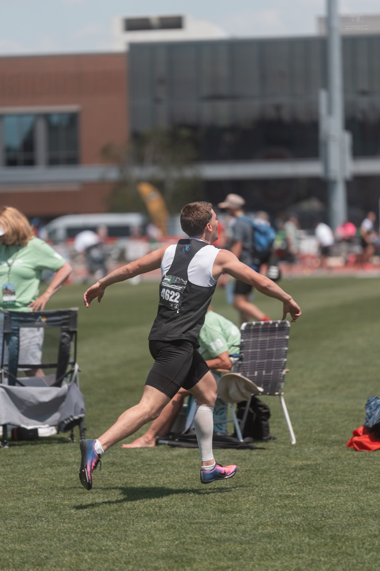 Male track athlete number 4622 sprinting on grass field during outdoor track and field competition.