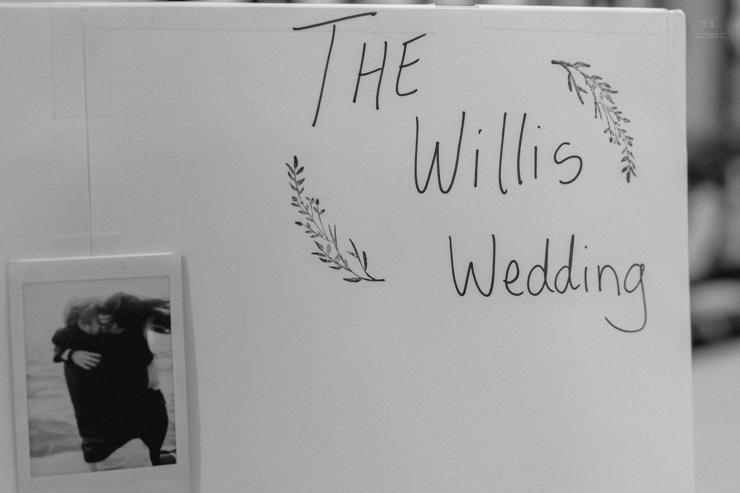 Black and white sign reading The Willis Wedding decorated with hand-drawn floral laurels.