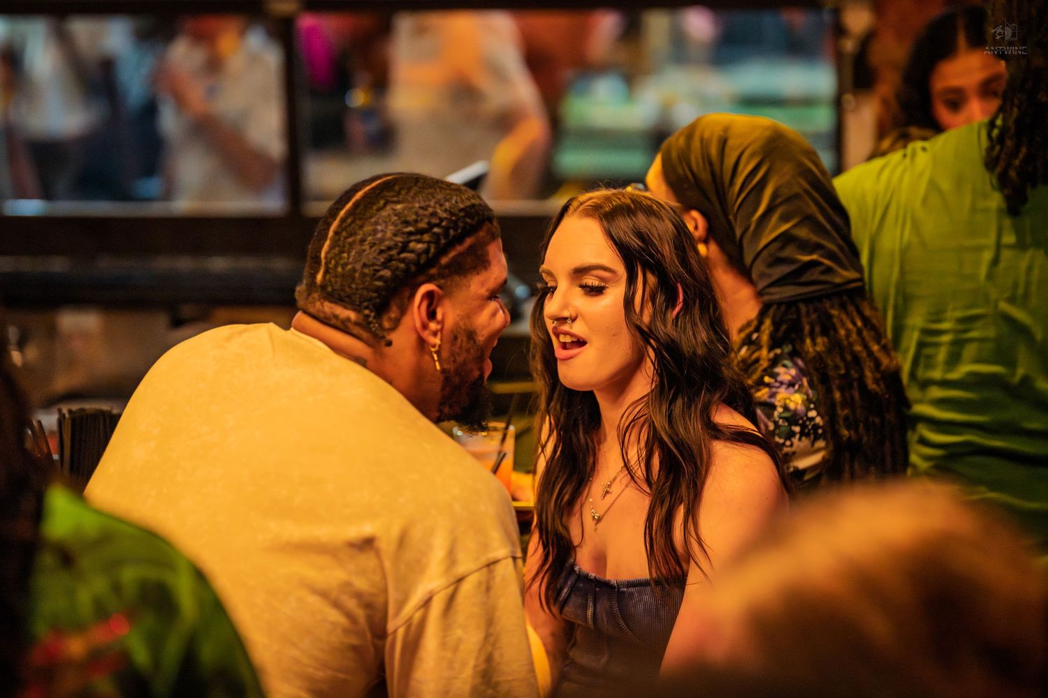 Lively crowded bar scene with people socializing under warm amber lighting at a social event.