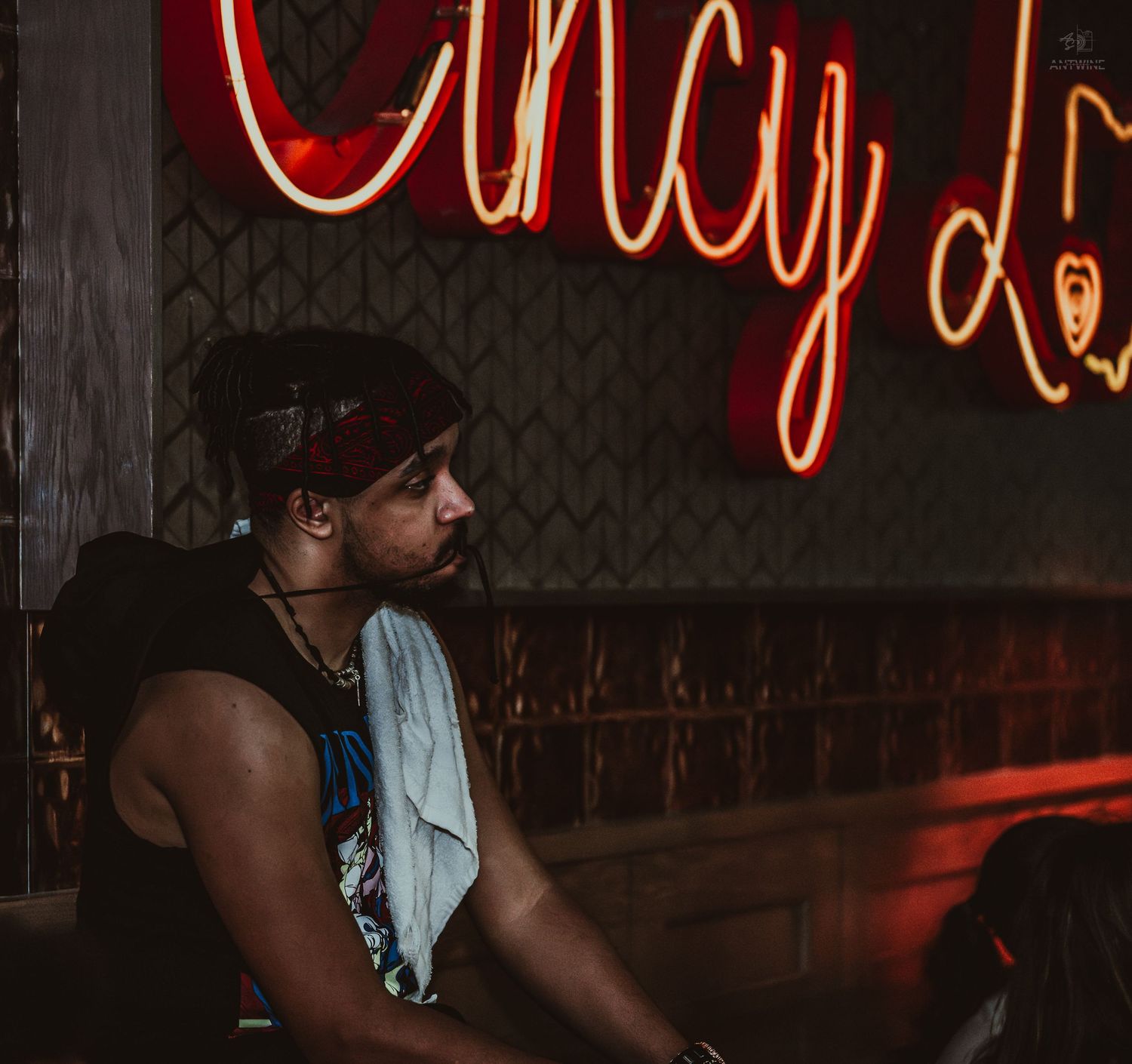 DJ with bandana performs under neon Cincy Love sign at a nightclub.
