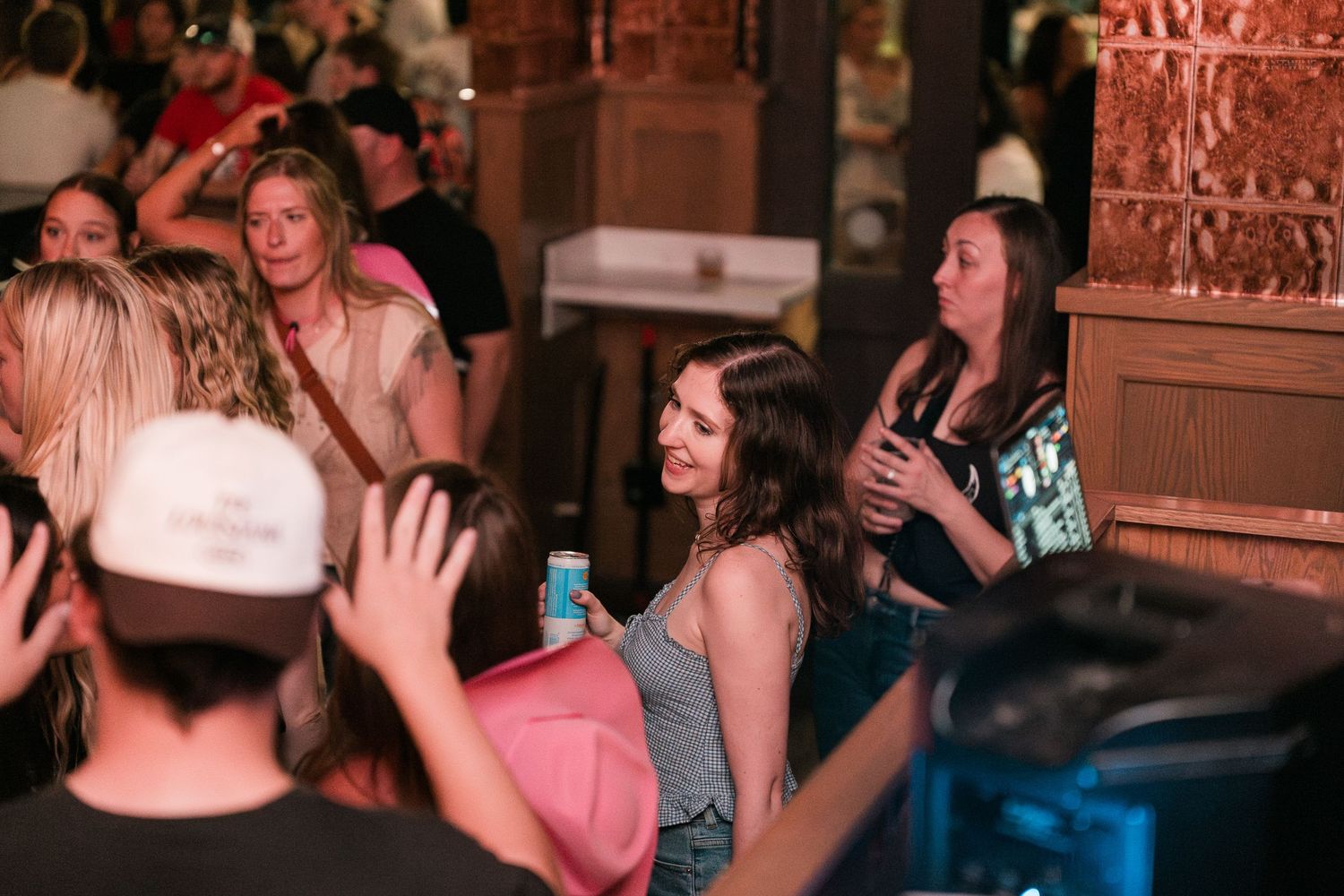Crowd of people socializing at a lively indoor bar event with warm ambient lighting.