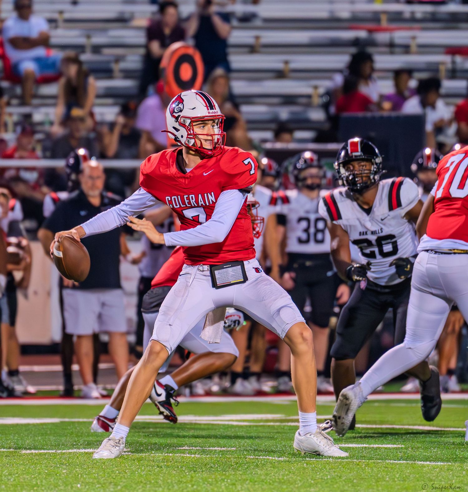 Colerain quarterback prepares to throw a pass during a high school football game under stadium lights.