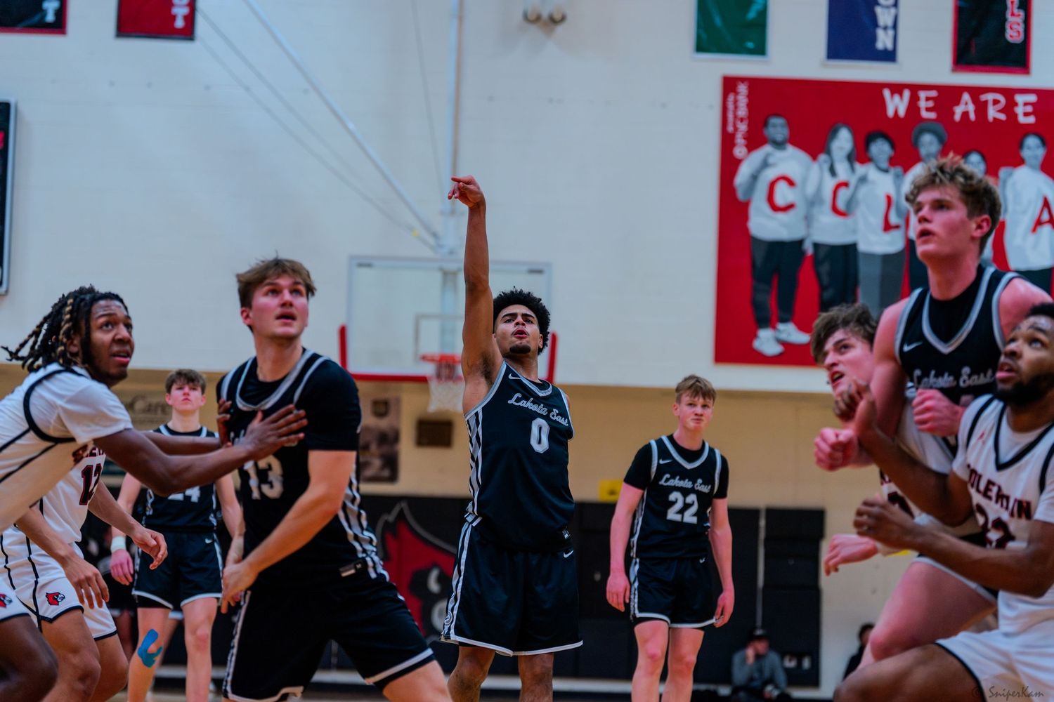 High school basketball players competing during an indoor game under gymnasium lights.