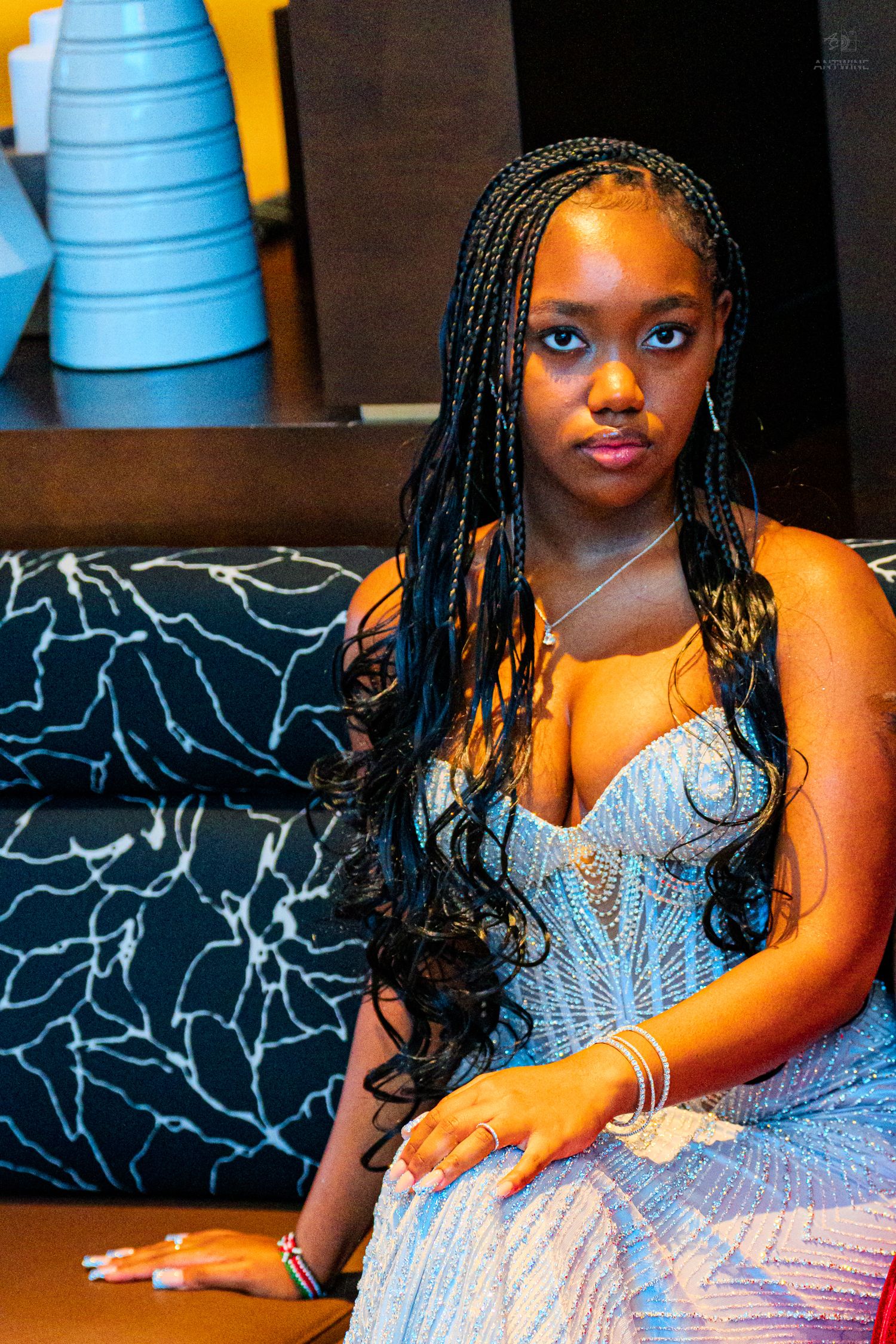 Close-up portrait of a young woman in a sparkling blue strapless gown with long braided hair.