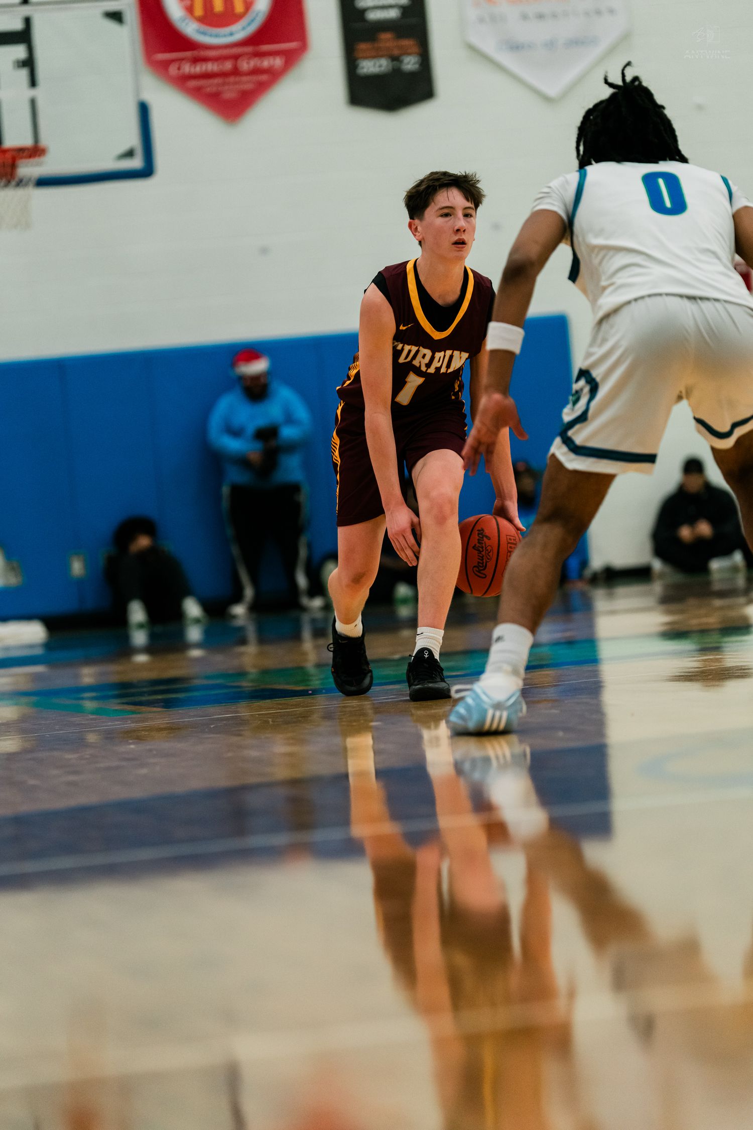 Turpin high school basketball player number 1 dribbles ball while being defended by opponent in white uniform.