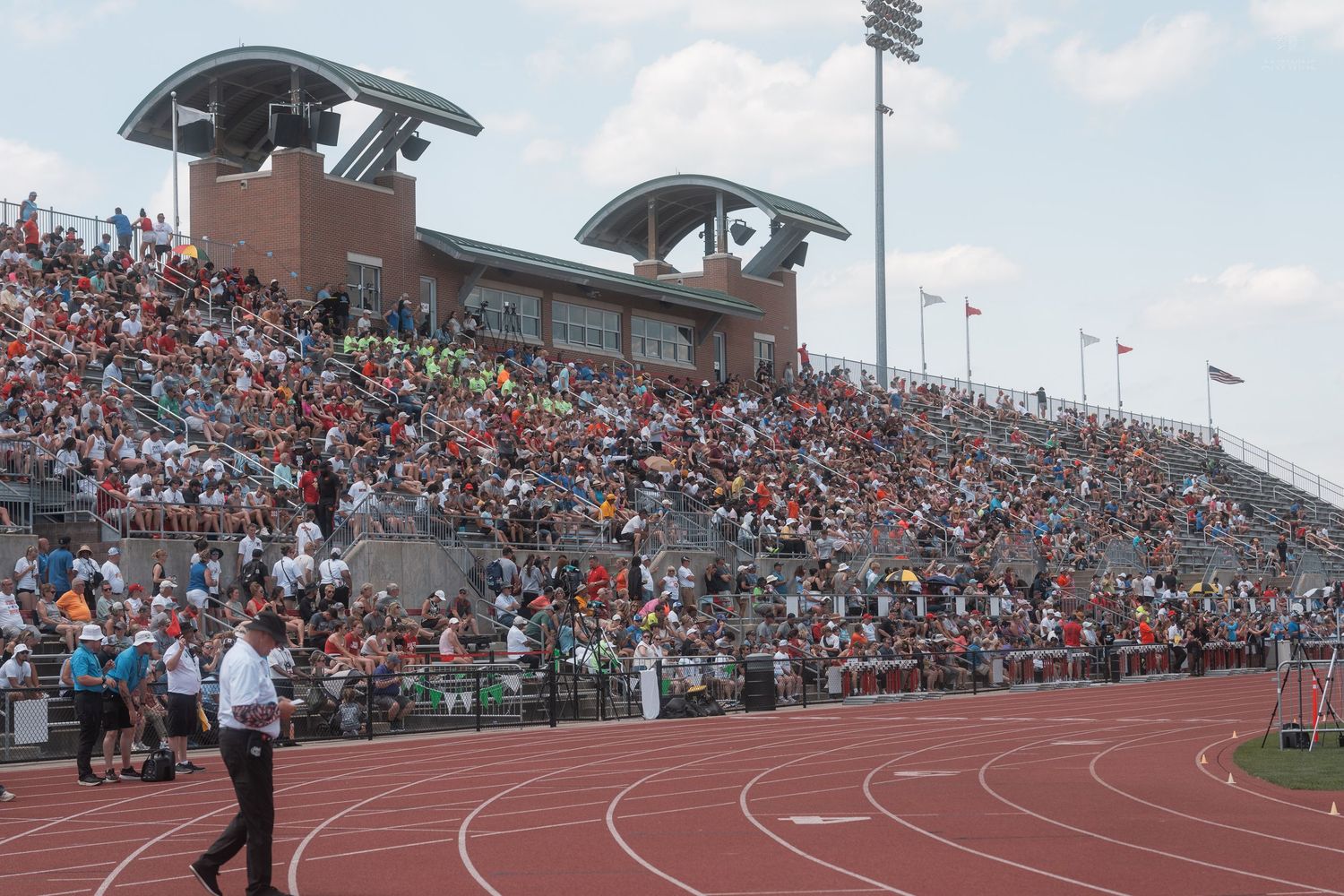 Large crowd fills the grandstands at Jesse Owens Memorial Stadium during an outdoor track and field championship event.