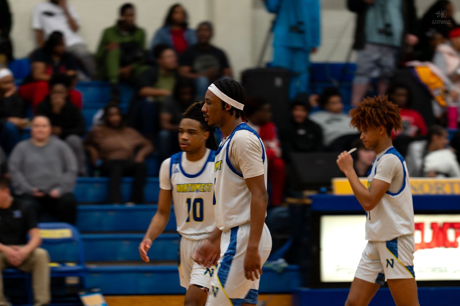 Three Northwestern high school basketball players celebrate on the court during a game.