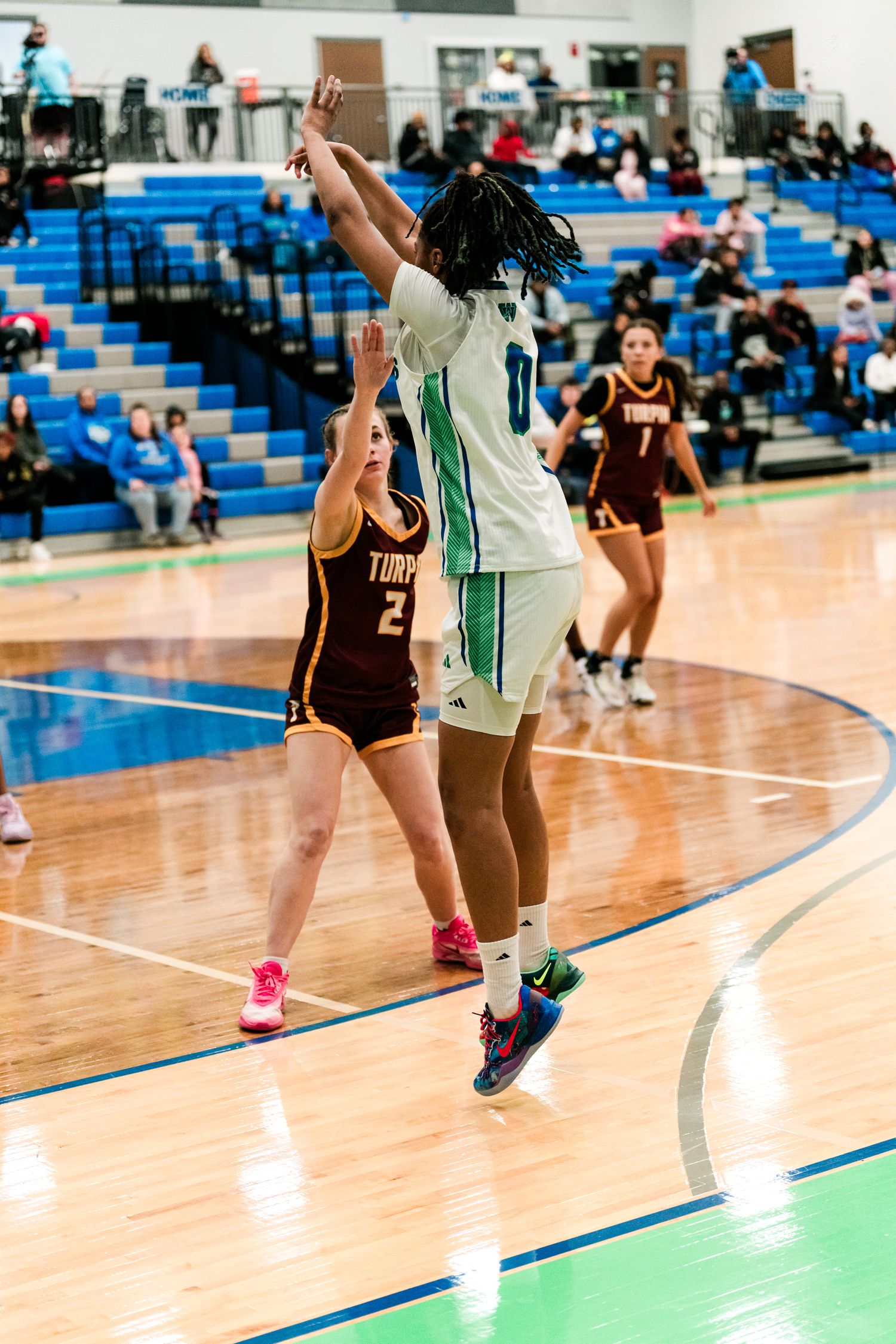 Warriors player #0 shoots over Turpin #2 defender during a girls high school basketball game.