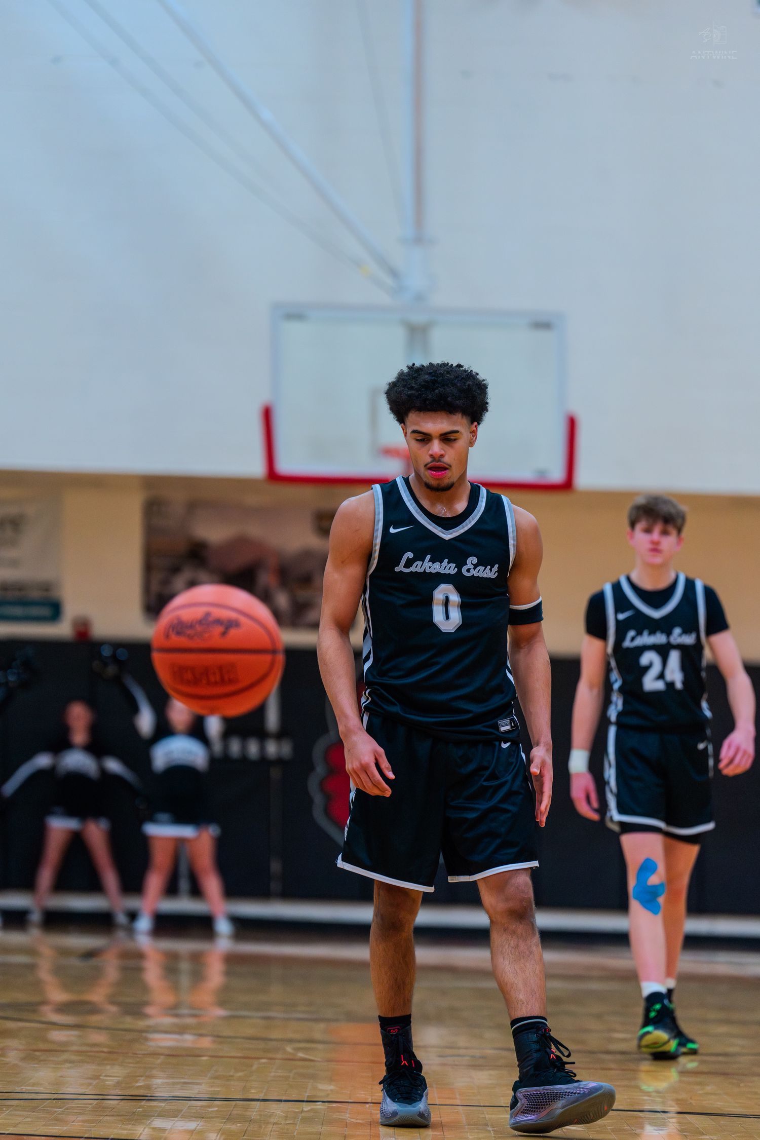 Lakota East player number 0 walks on court as basketball bounces nearby during a high school game.
