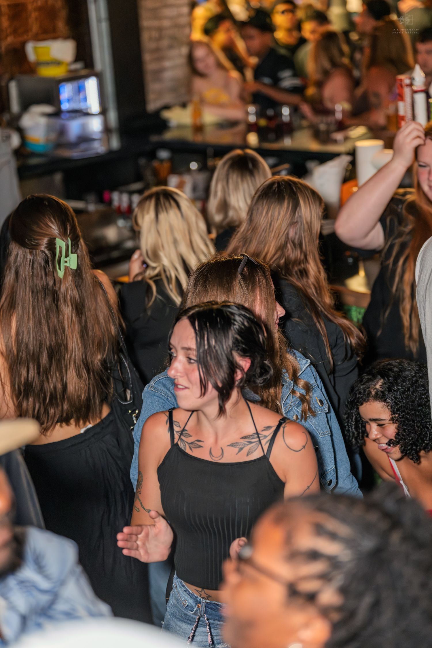 Crowd of young women dancing and socializing at a busy bar or nightclub event.