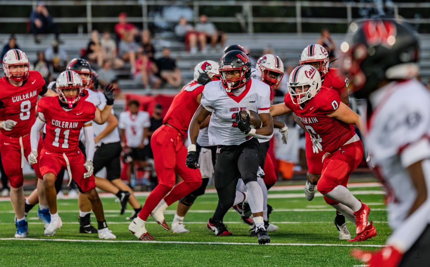 Colerain football players in red uniforms tackle an opponent during an intense high school football game.