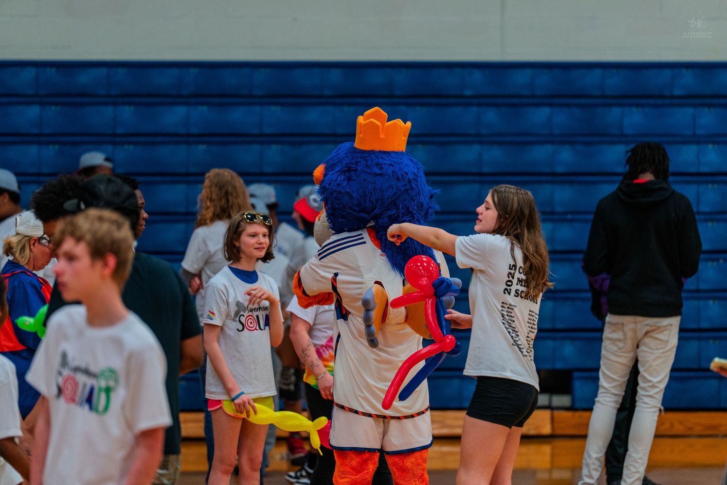 Students interact with a mascot in a school gymnasium during a spirited pep rally event.