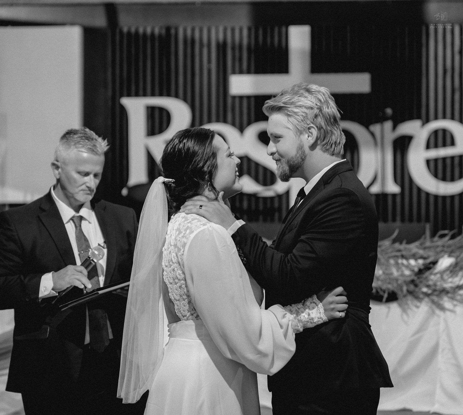 Bride and groom share a tender moment at the altar during their indoor wedding ceremony.