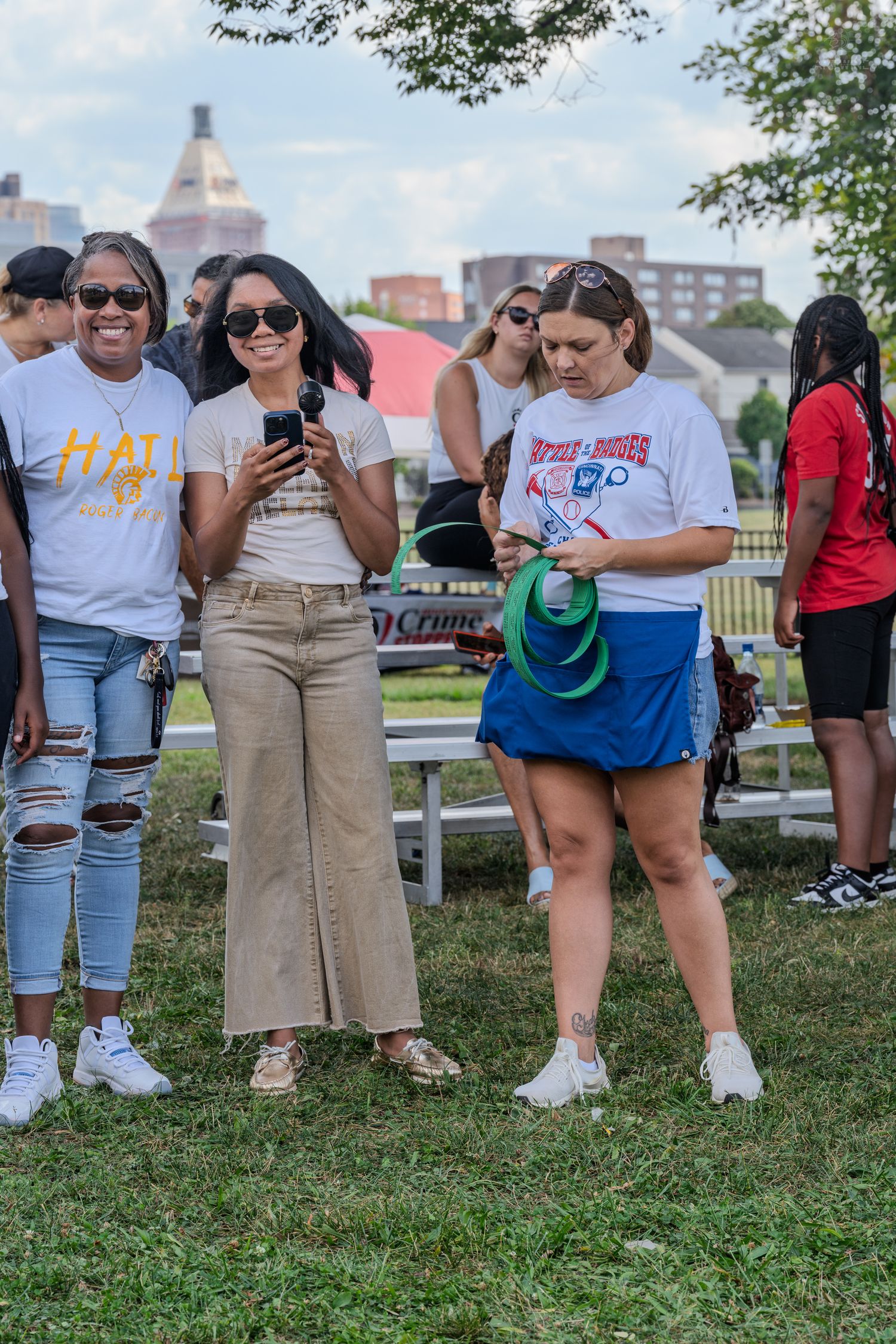 Group of women in casual attire gathered outdoors at community event on sunny day.
