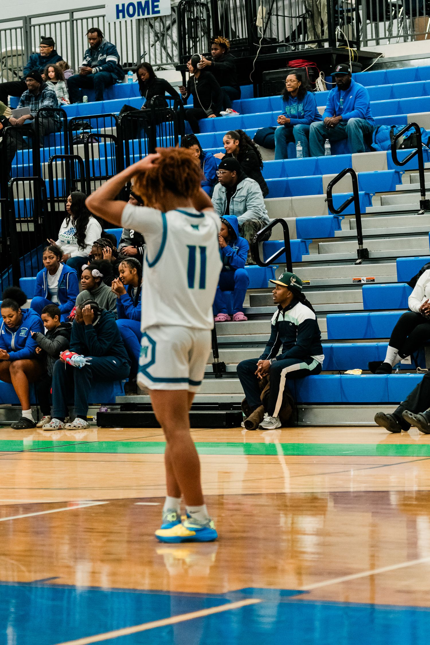Warriors #11 player stands on court with hands on head before packed home gymnasium crowd.