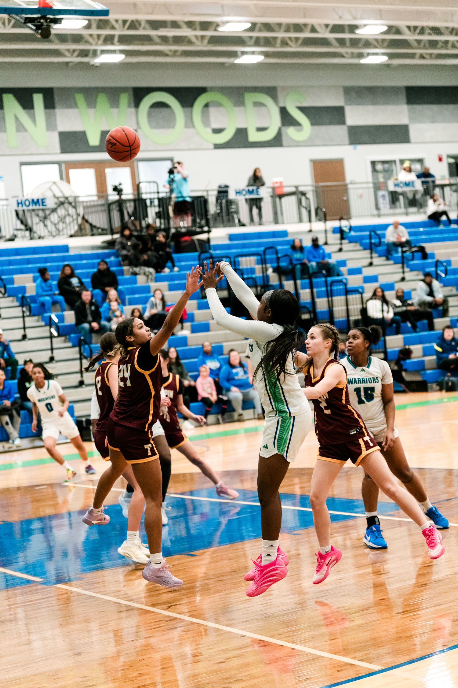 Girls basketball players jump for a contested rebound near the basket during a high school game at Mason Woods gymnasium.