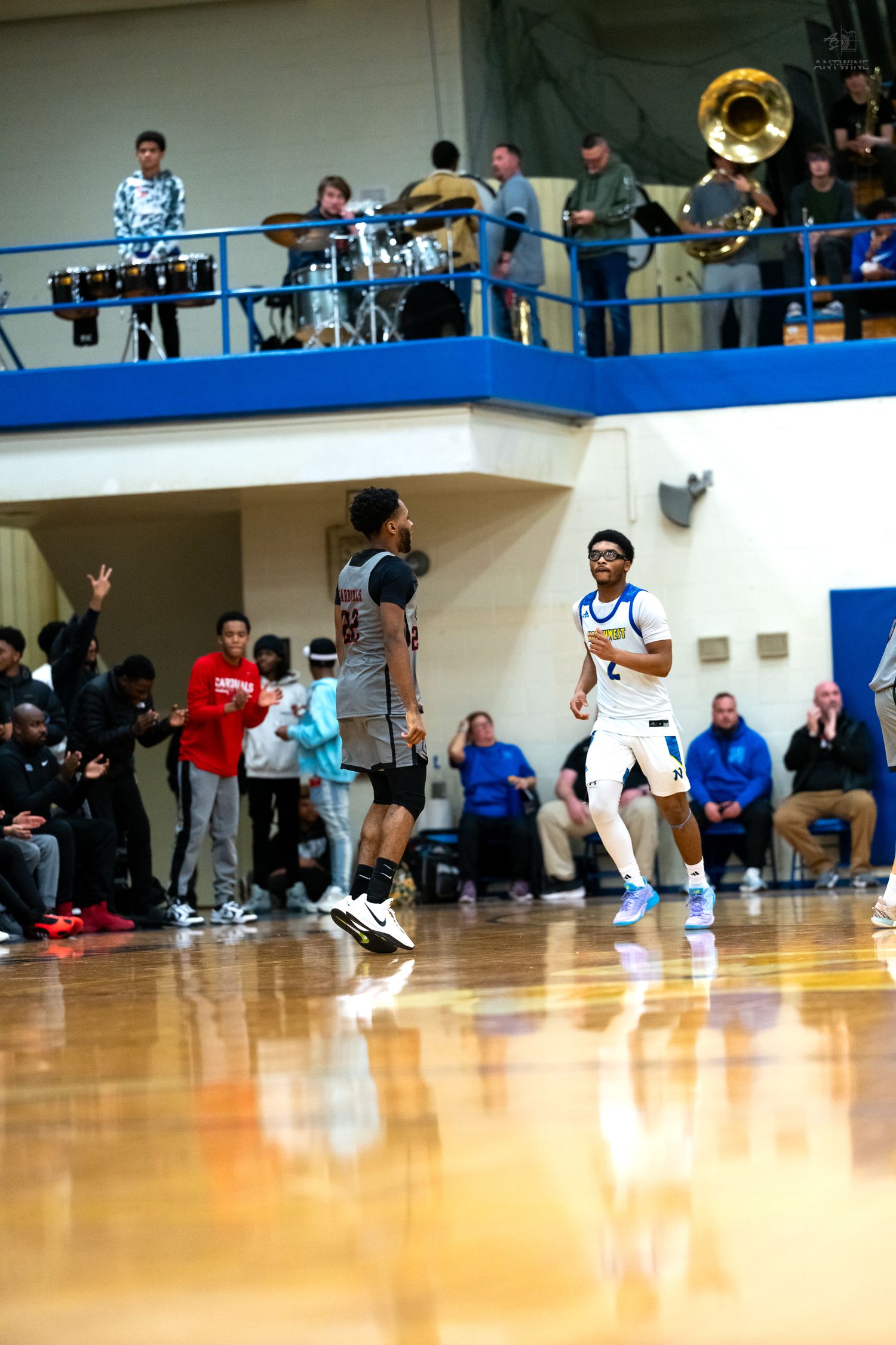 Two high school basketball players face off near sideline during competitive indoor gym game.