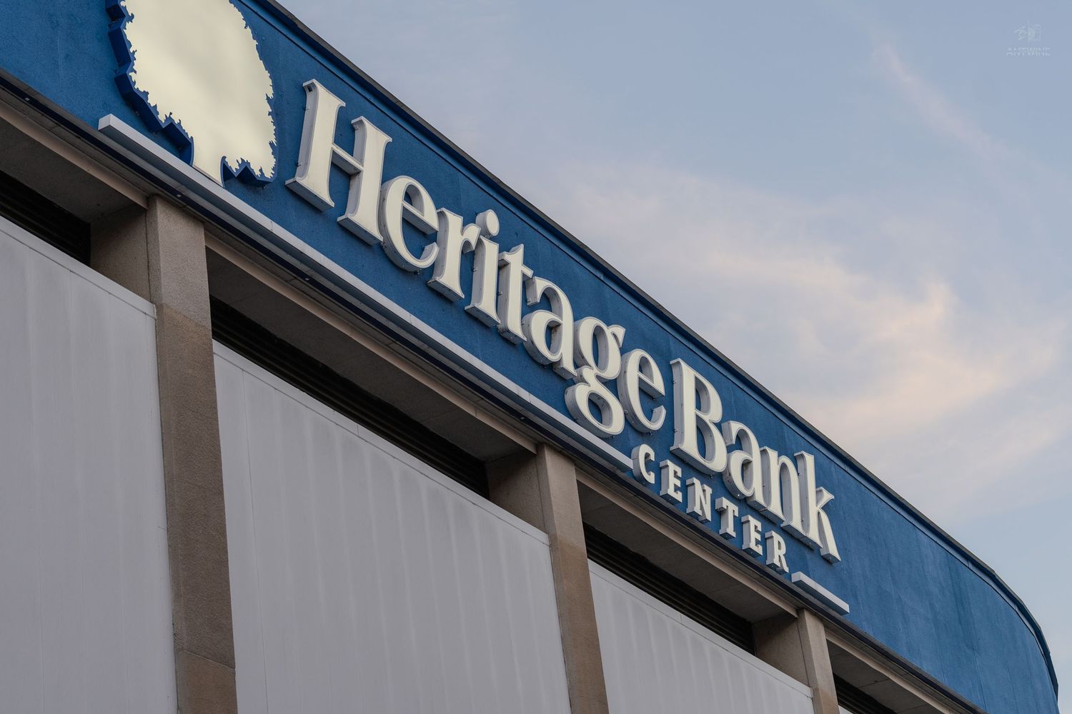 Heritage Bank Center arena sign displayed on the exterior of the building against a blue sky.