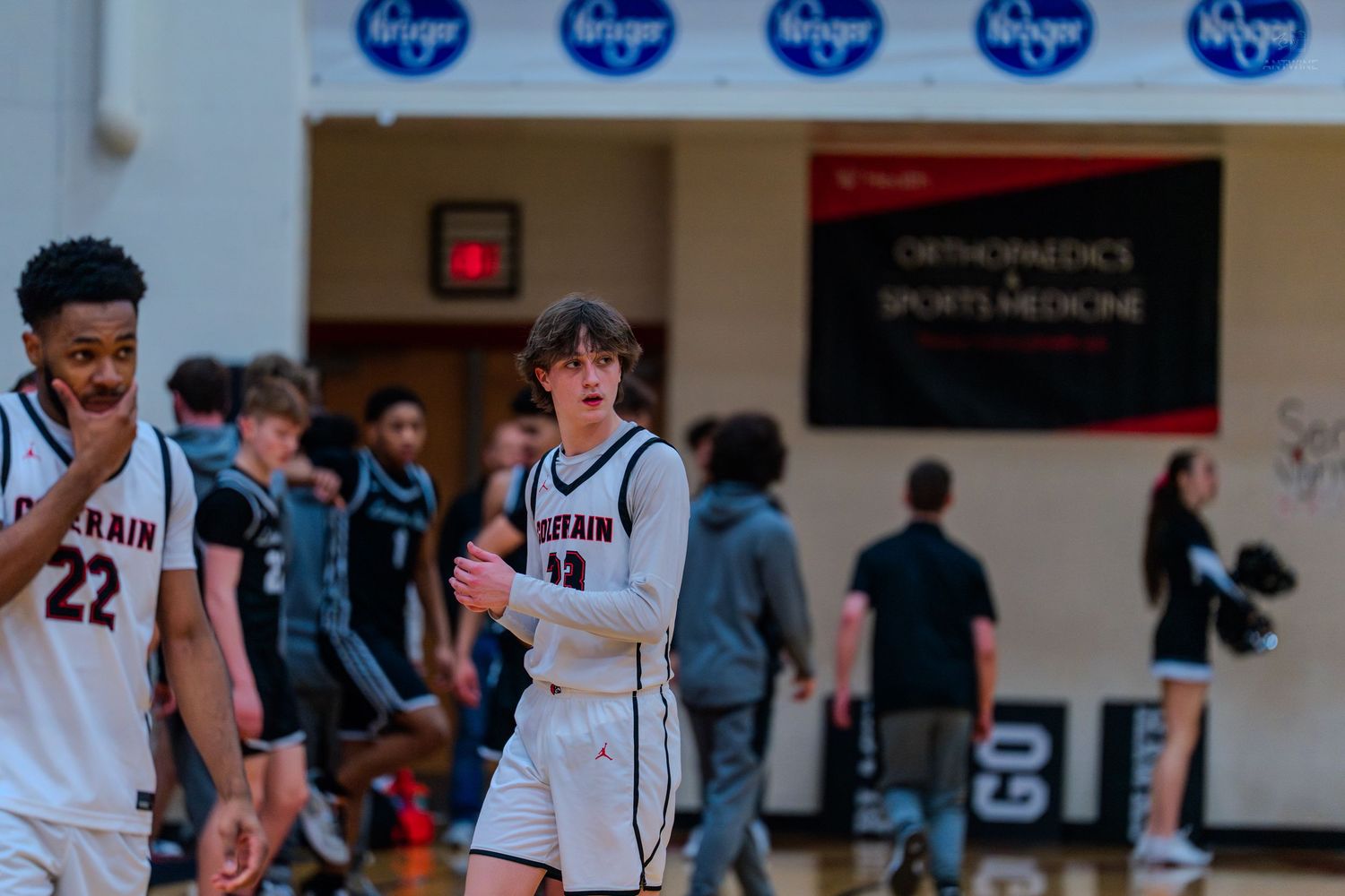 Two Lorrain high school basketball players walk on court during game.