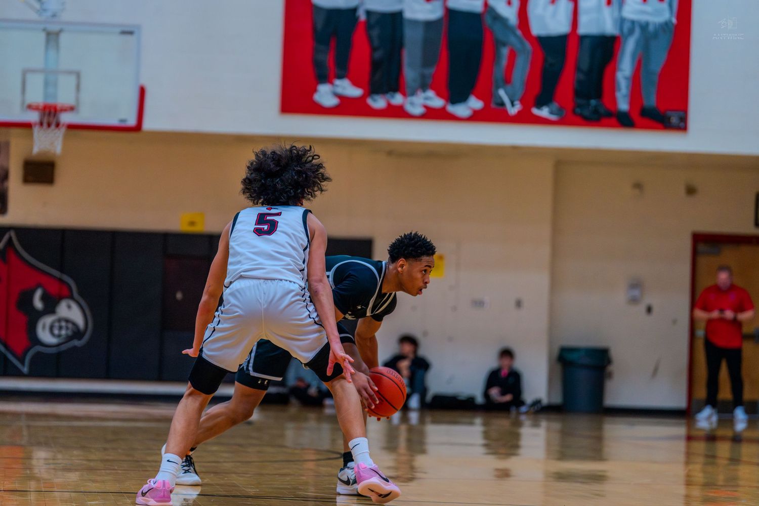 Lakota East player #0 dribbles the ball while defended by opponent #5 in high school basketball game.